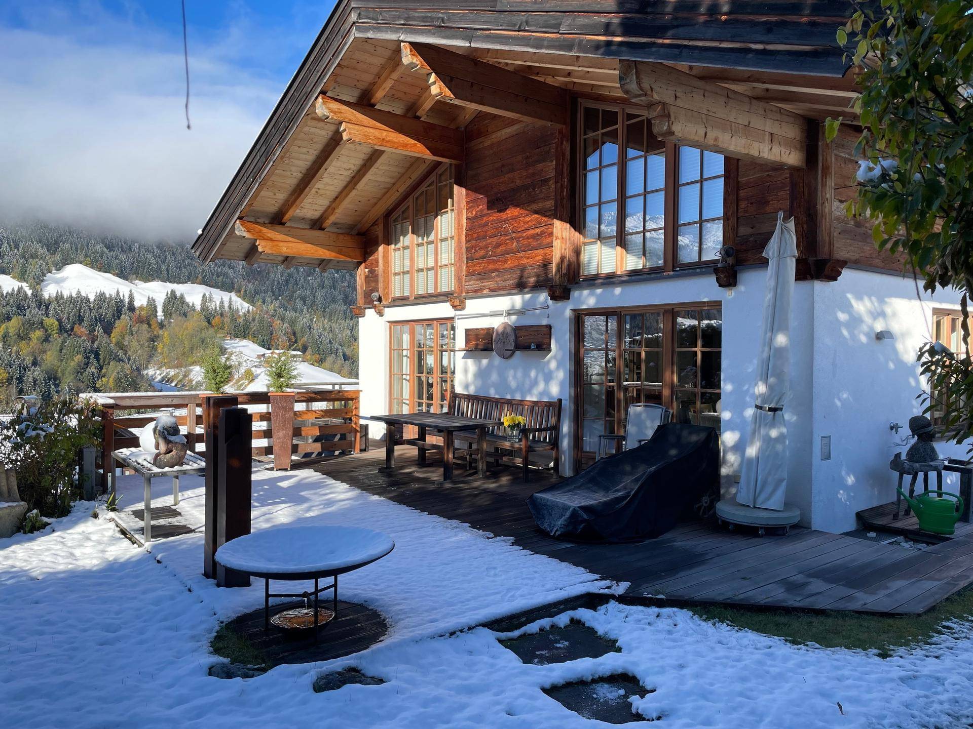 Großzügige Holzterrasse vor dem Haus mit Bergblick und winterlicher Schneelandschaft.