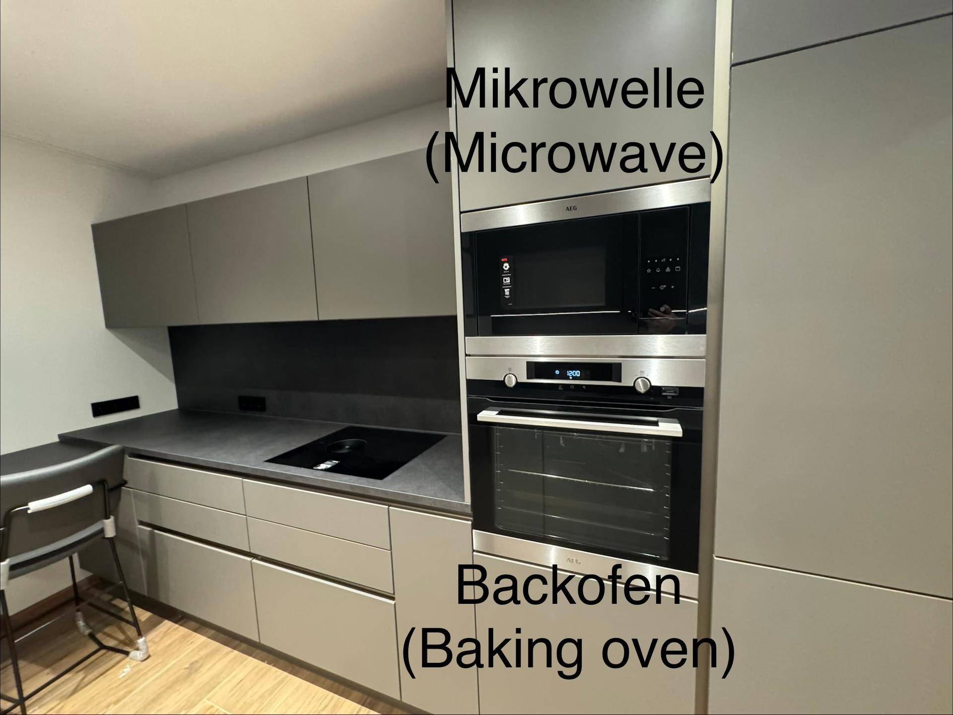 Integrierte Mikrowelle und Backofen in einer modernen Küche mit dunklen Fronten.