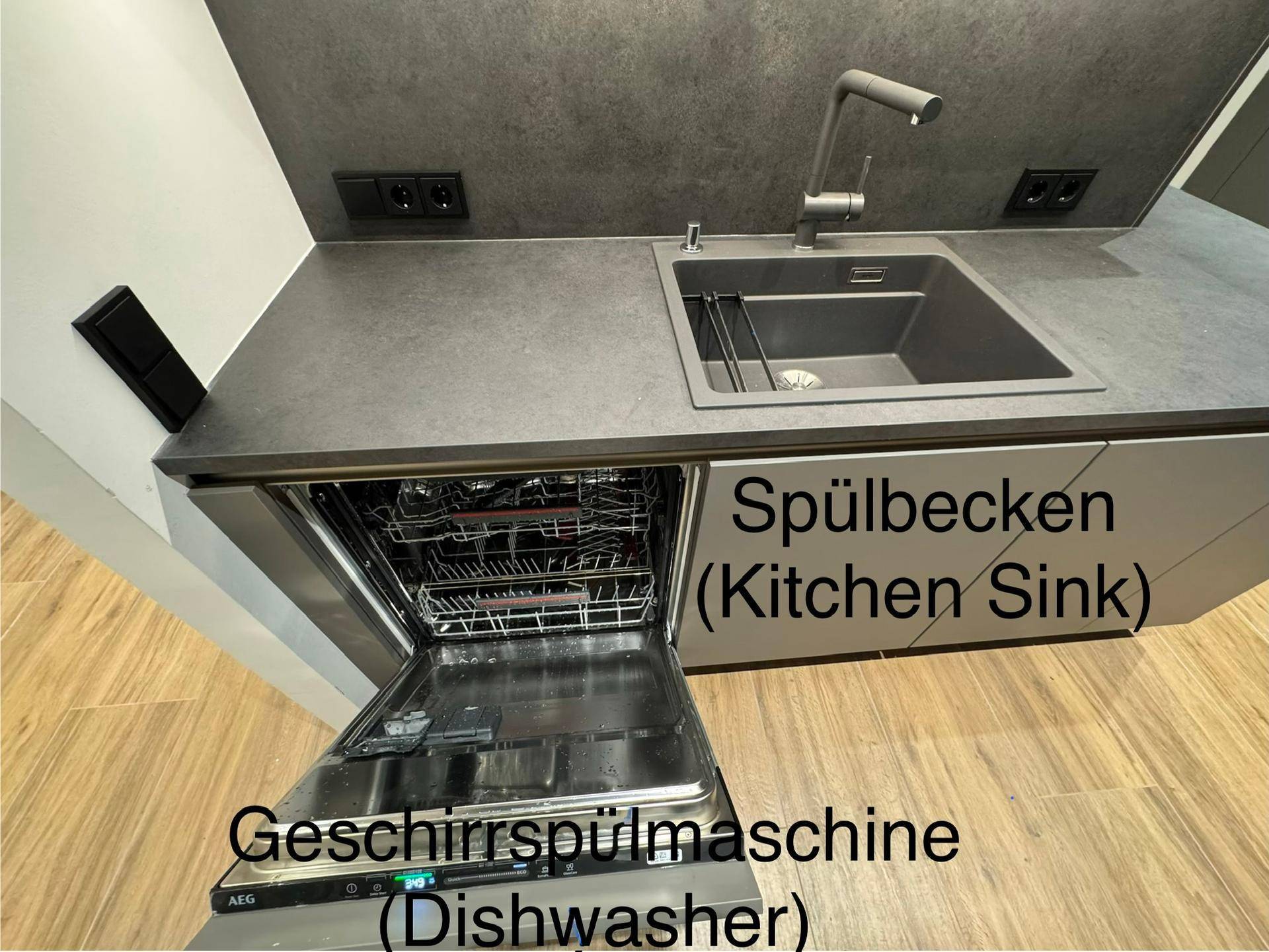 Integrierte Spülmaschine und modernes Spülbecken in der grauen Küchenzeile.
