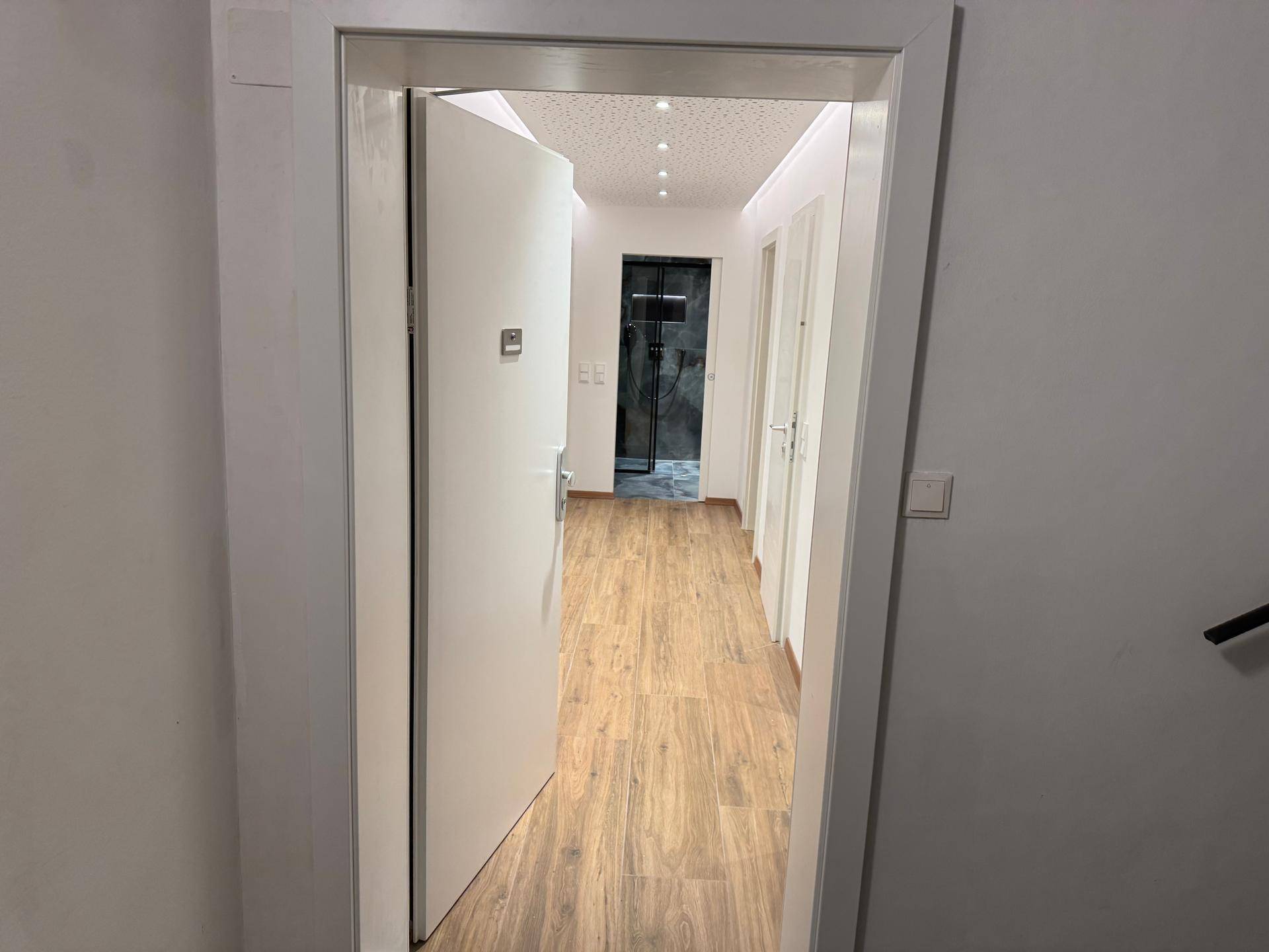 Heller Flur mit Holzboden und Blick in weitere Räume und ein modernes Badezimmer.