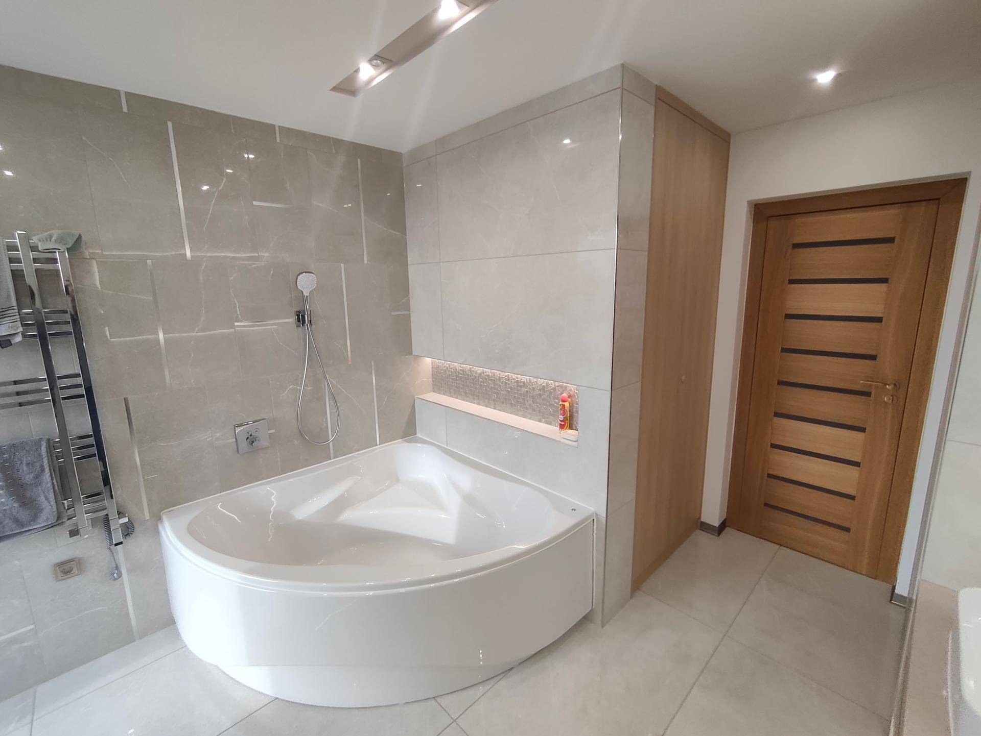 Modernes Badezimmer mit Eckbadewanne und großformatigen Fliesen.