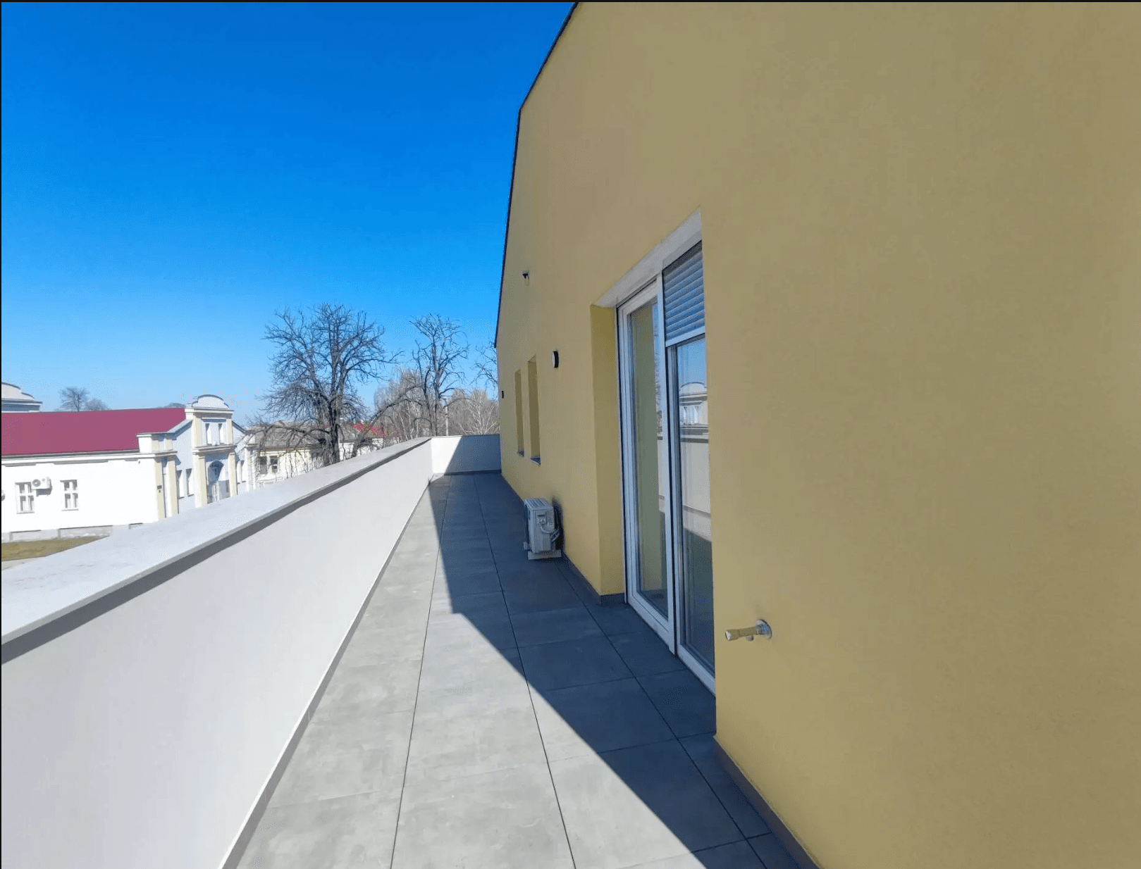 Lange, schmale Terrasse mit Fliesenboden und Blick auf die Umgebung, ausgestattet mit Klimaanlage.