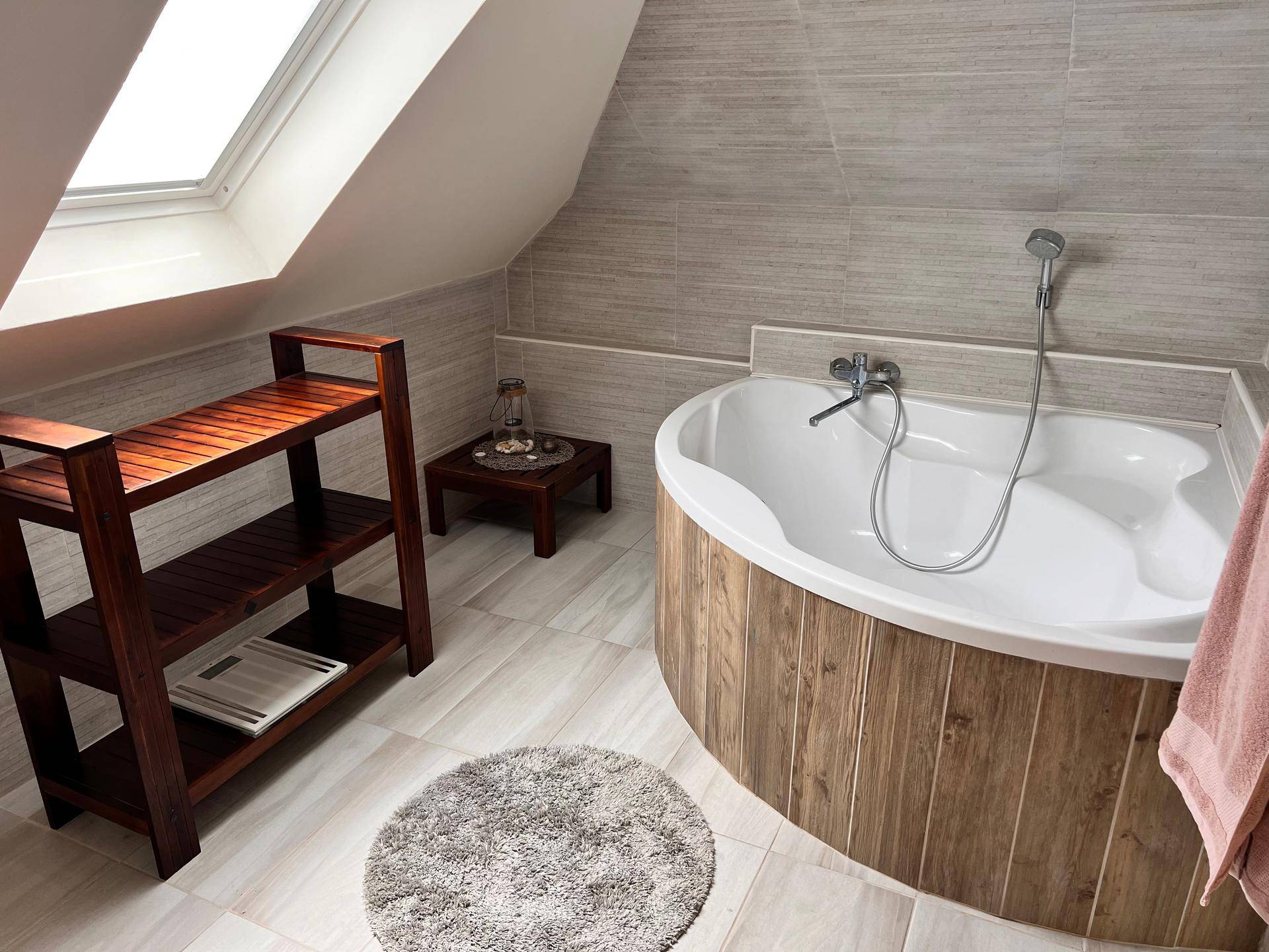 Helles Badezimmer im Dachgeschoss mit Badewanne, Dachfenster und modernen Fliesen.