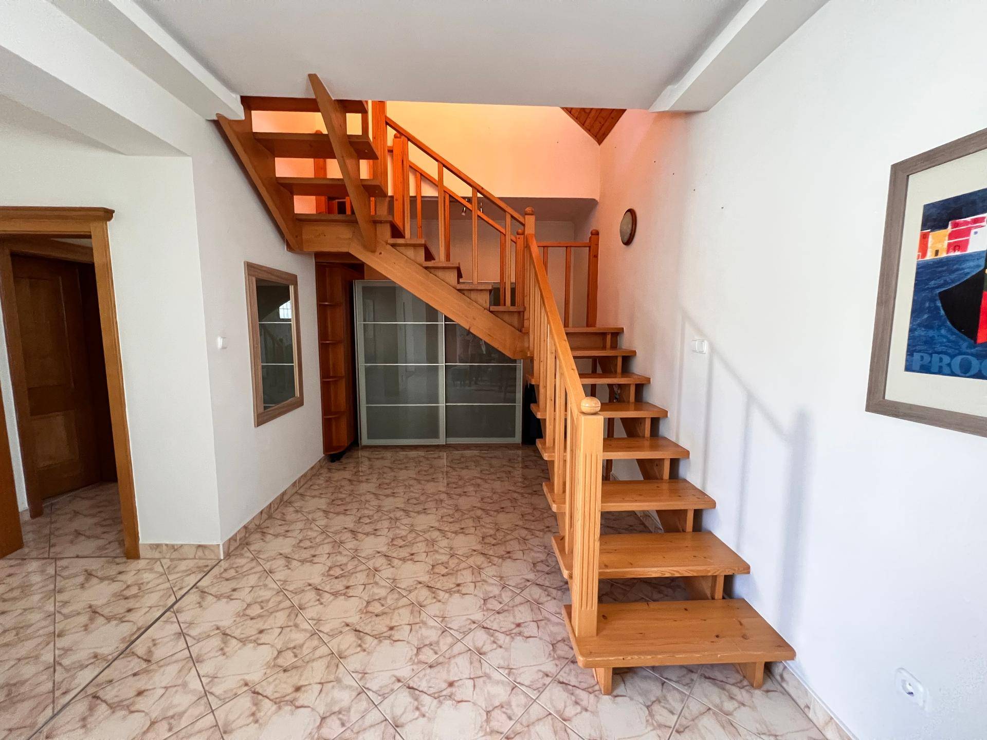 Heller Flur mit Holztreppe und gemustertem Fliesenboden.