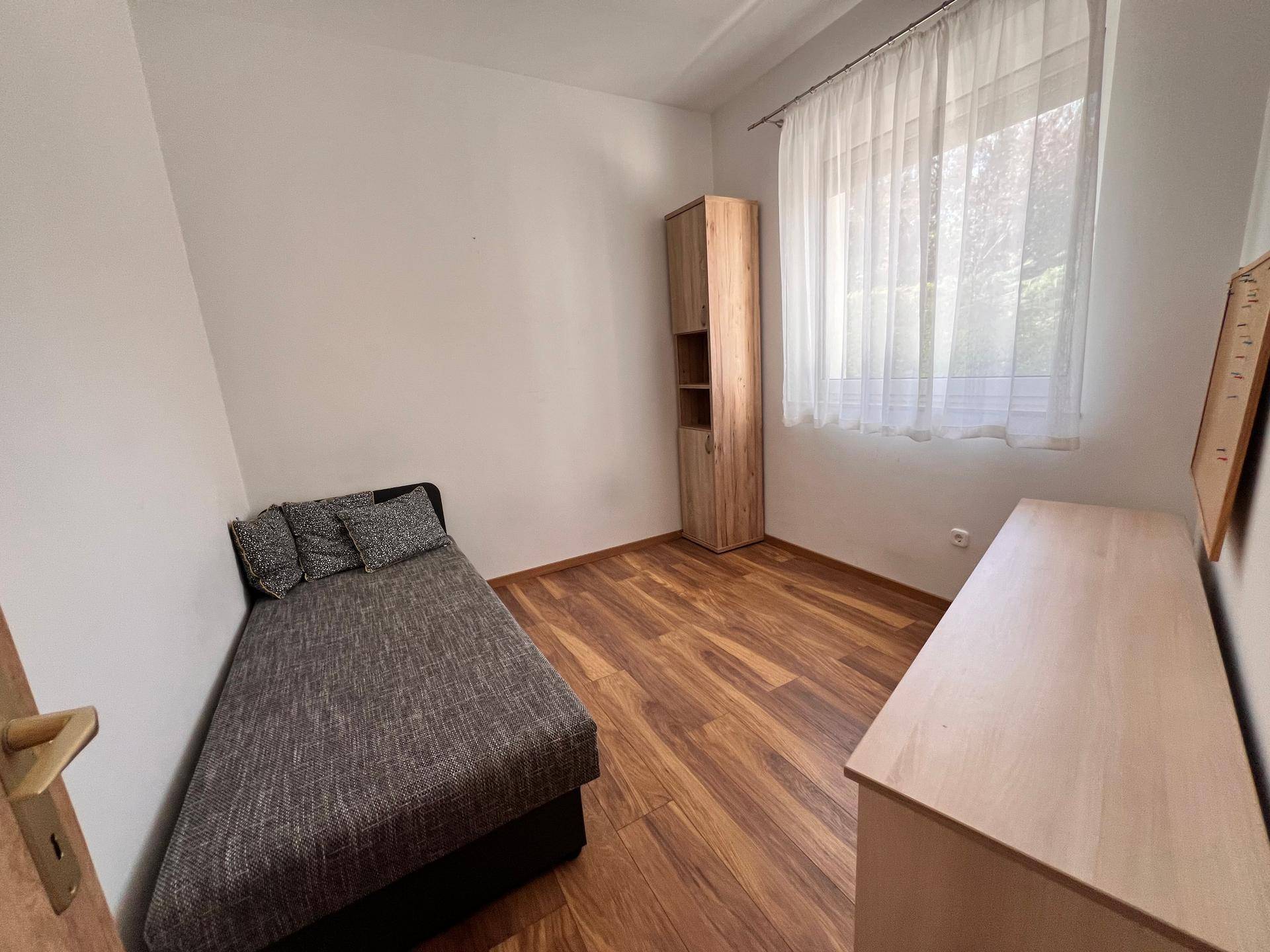 Kleines Schlafzimmer oder Gästezimmer mit Holzboden und einfacher Einrichtung.