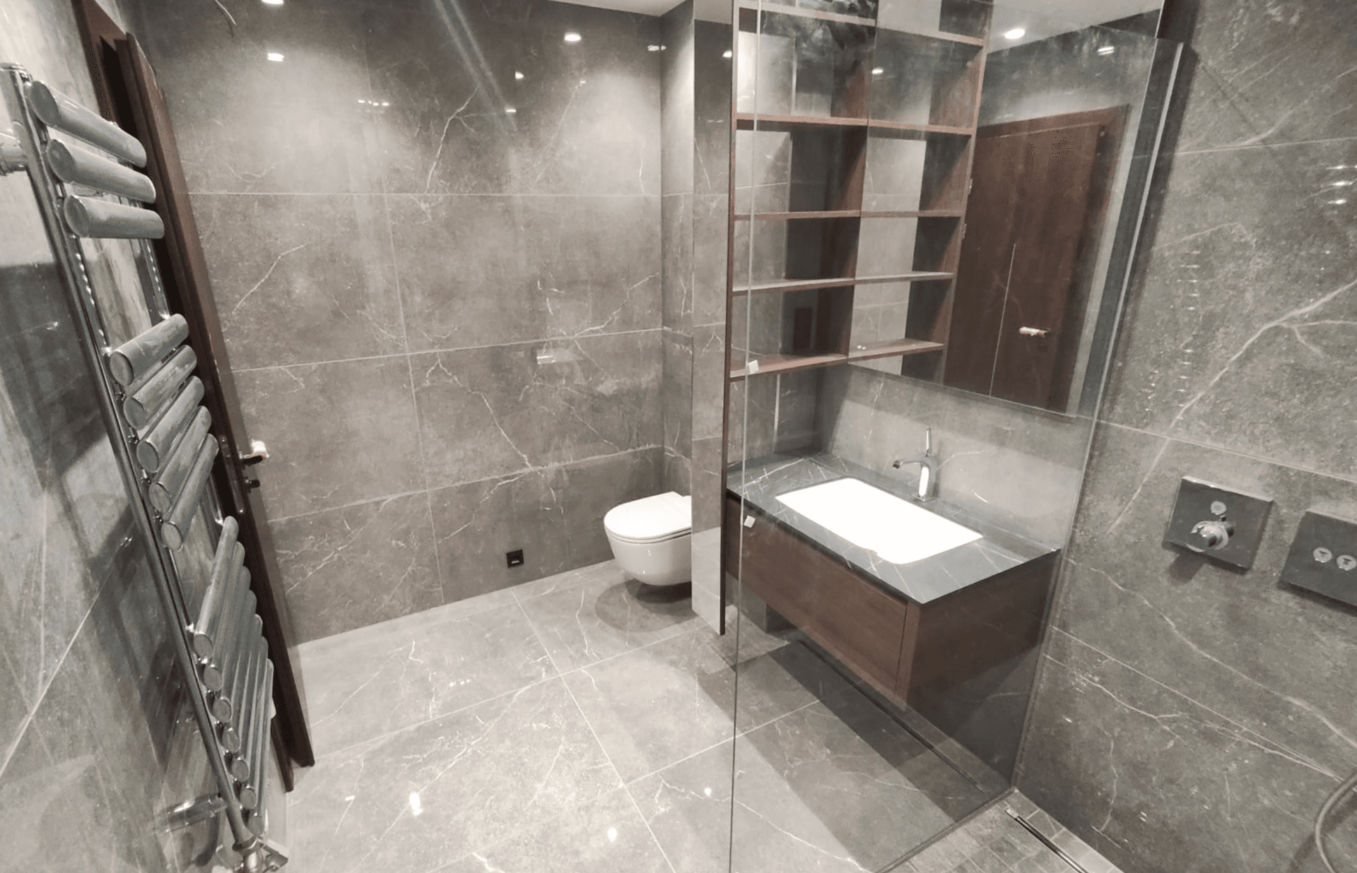 Elegantes Badezimmer mit grauen Marmorfliesen, modernem Waschtisch und wandhängendem WC.