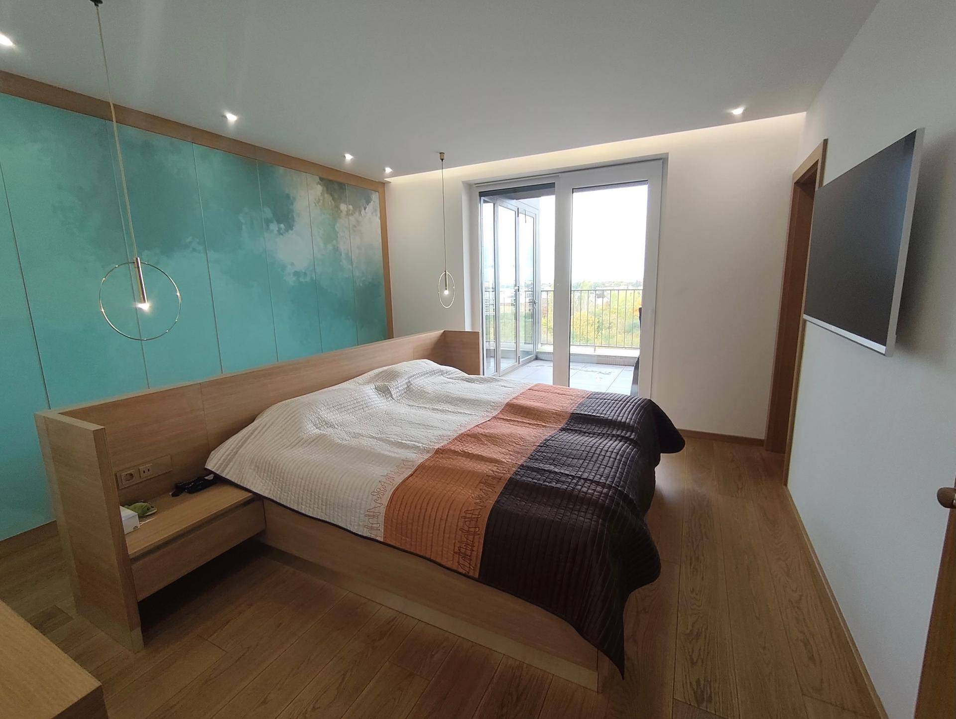 Modernes Schlafzimmer mit Holzbett, farbiger Akzentwand und Balkonzugang.