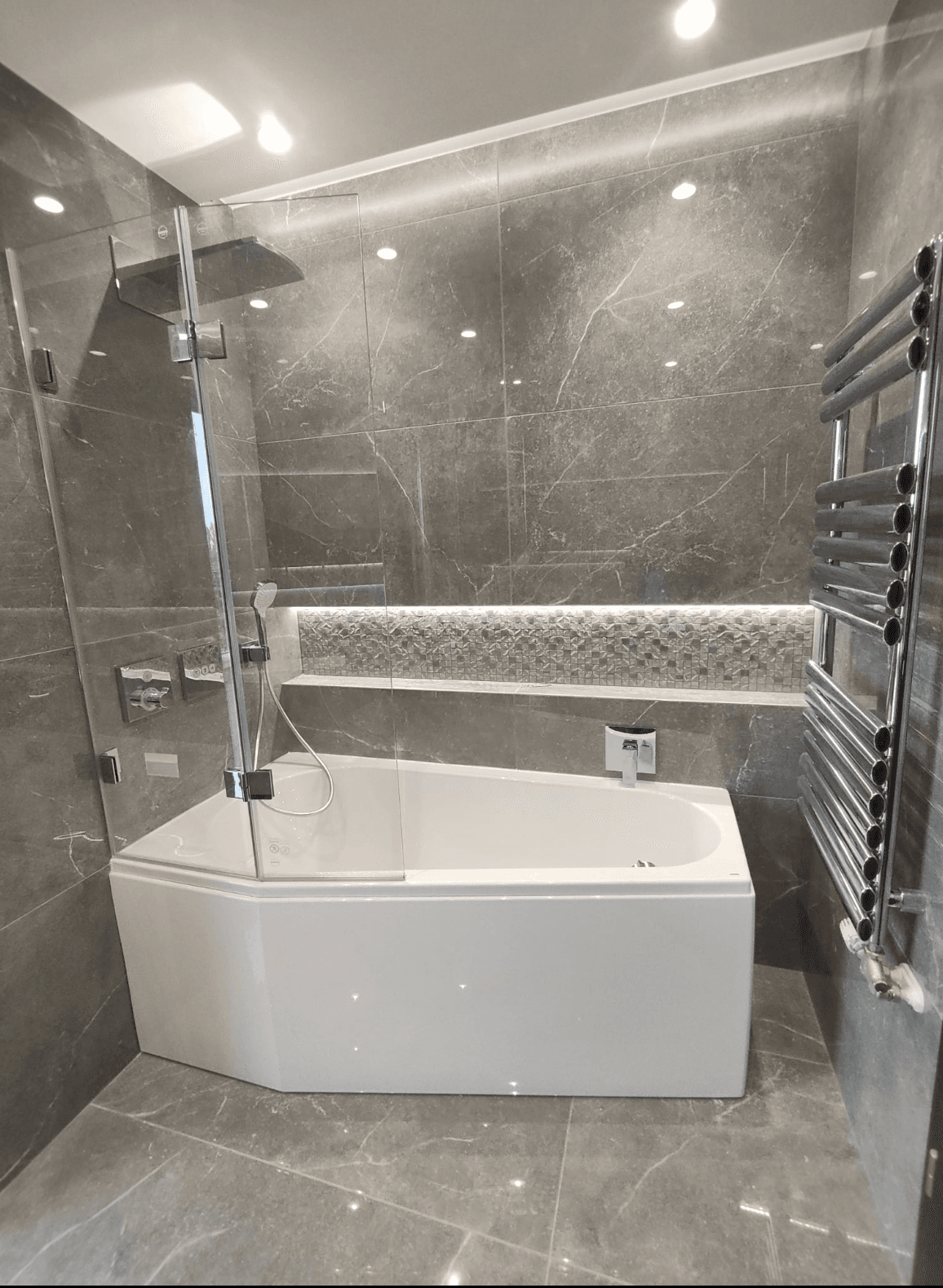 Modernes Badezimmer mit Eckbadewanne, Glasduschabtrennung und beheiztem Handtuchhalter.