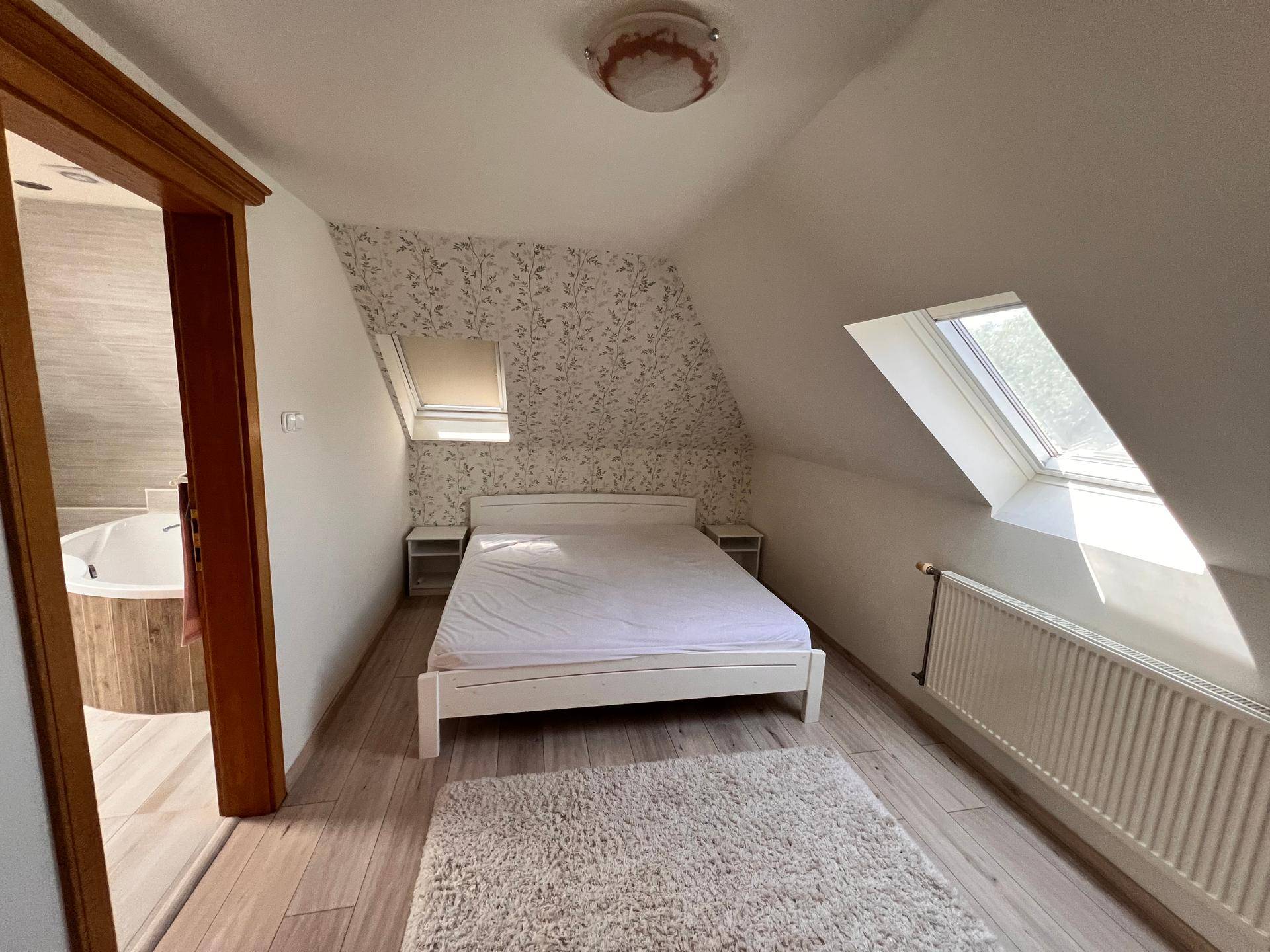Gemütliches Schlafzimmer im Dachgeschoss mit Doppelbett, Dachfenster und Zugang zum Bad.