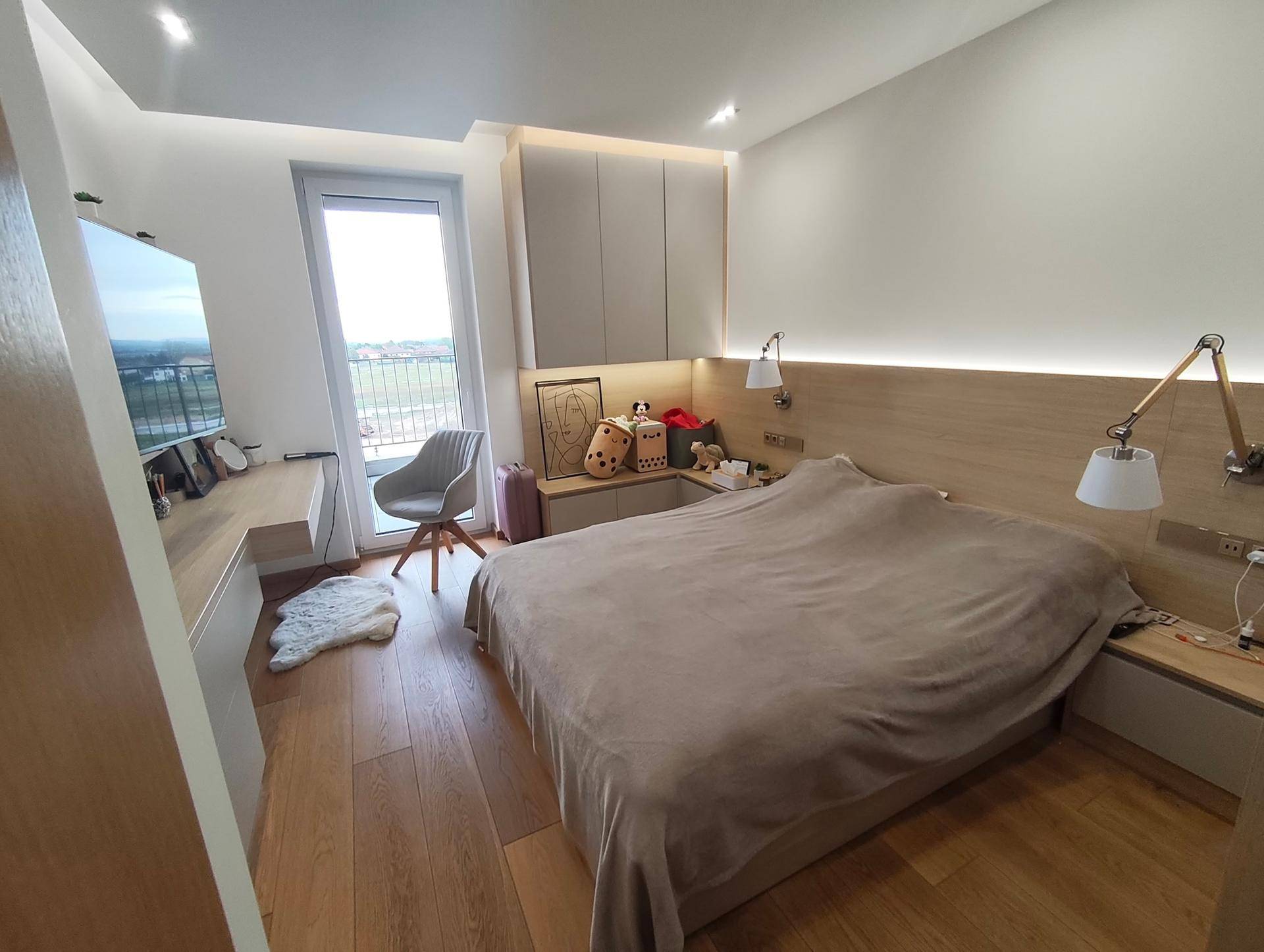 Gemütliches Schlafzimmer mit Holzboden, Schreibtisch und Balkonzugang.
