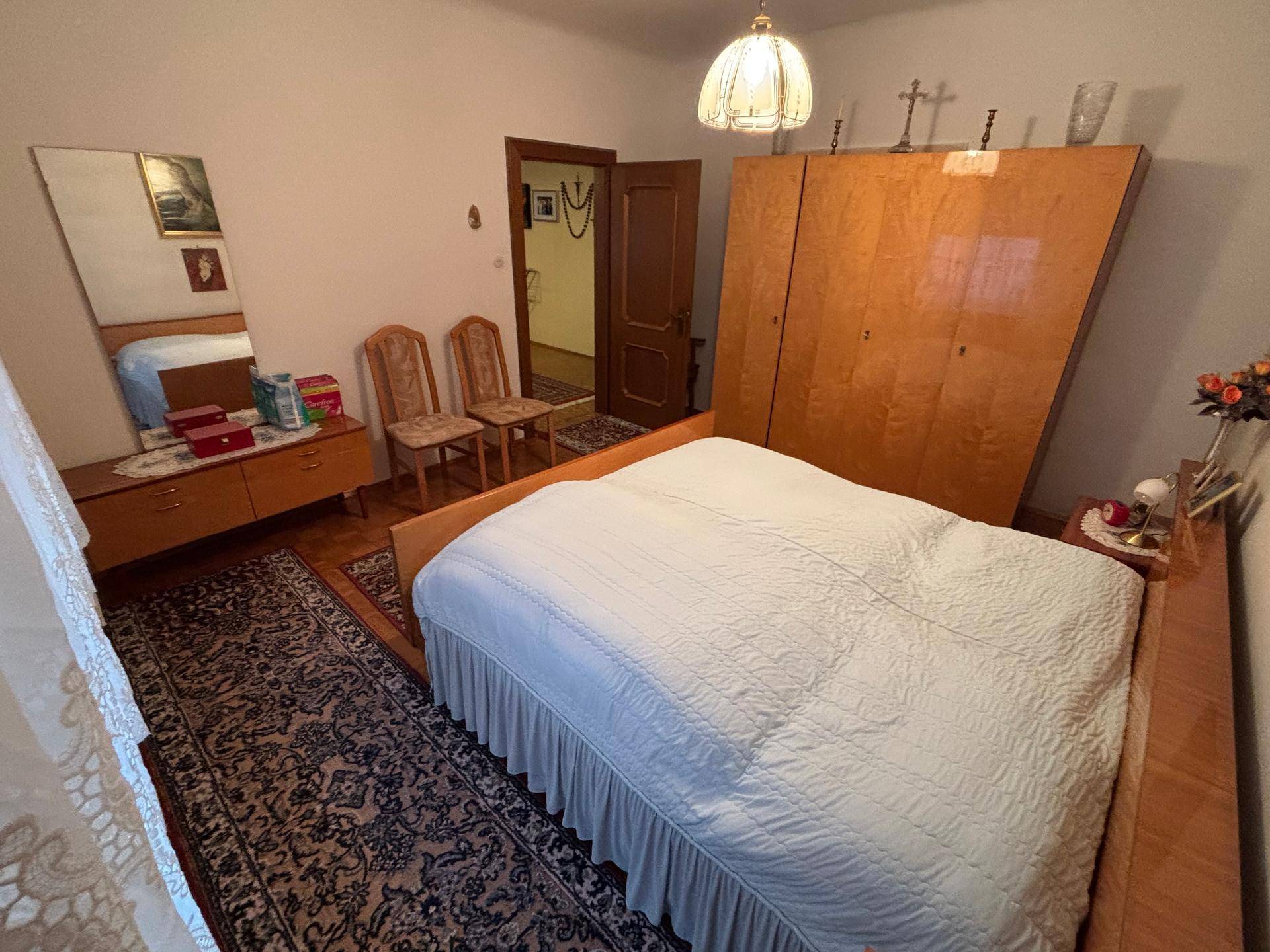 Geräumiges Schlafzimmer mit Doppelbett, Teppichläufern und einem großen Holzschrank im traditionellen Stil.