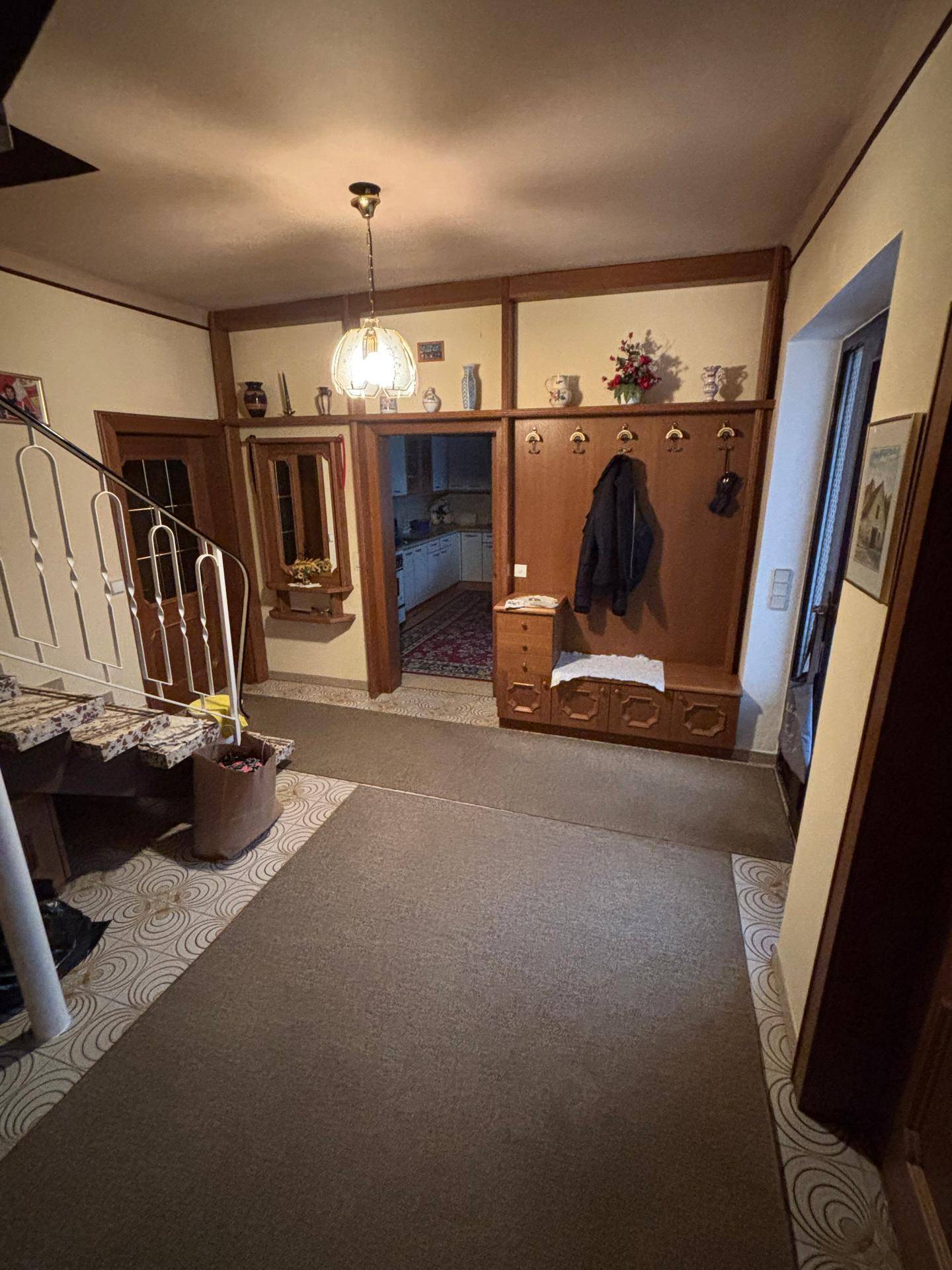 Eingangsbereich mit Teppichboden, Holzvertäfelung und einer Treppe, die in die obere Etage führt.