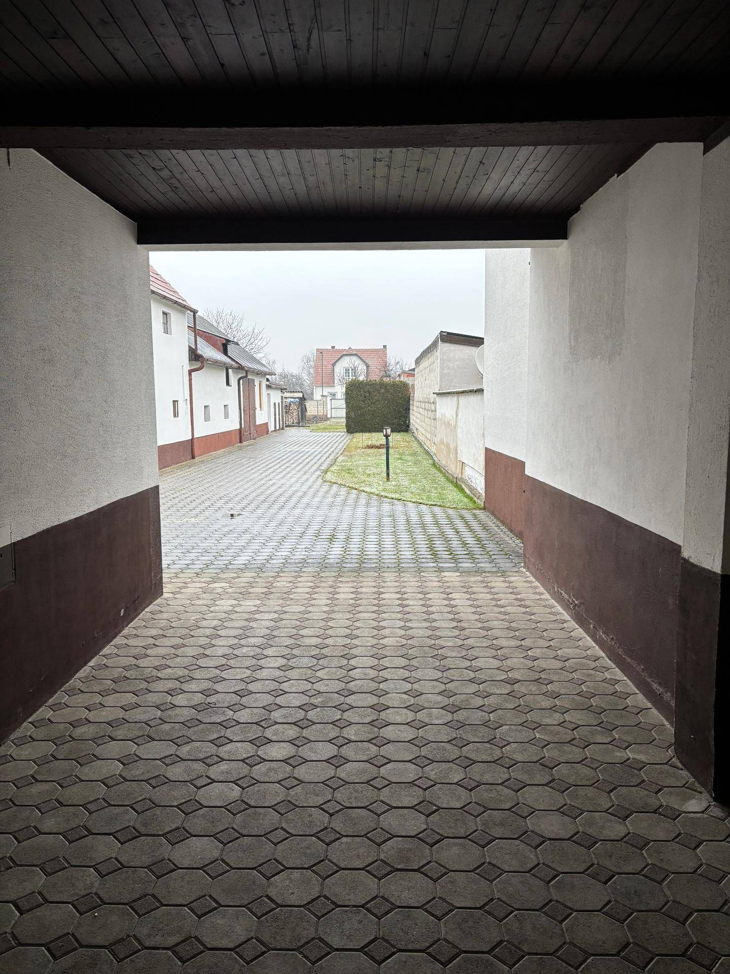 Gepflasterter Hofbereich mit Zugang zu weiteren Gebäuden und einem kleinen Rasenstück im Hintergrund.