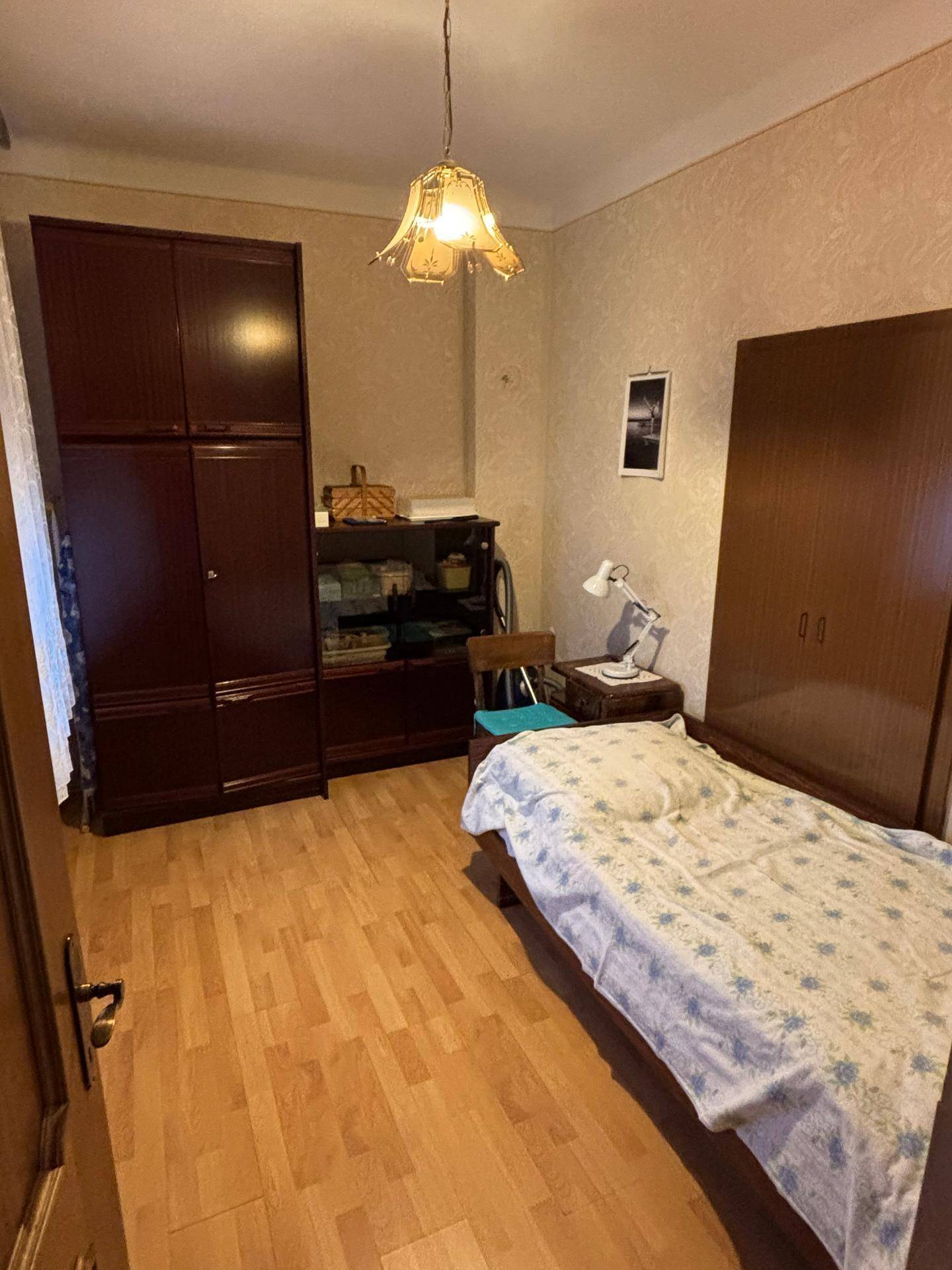 Schlafzimmer mit Laminatboden, Einzelbett und dunklen Holzmöbeln in traditionellem Stil.