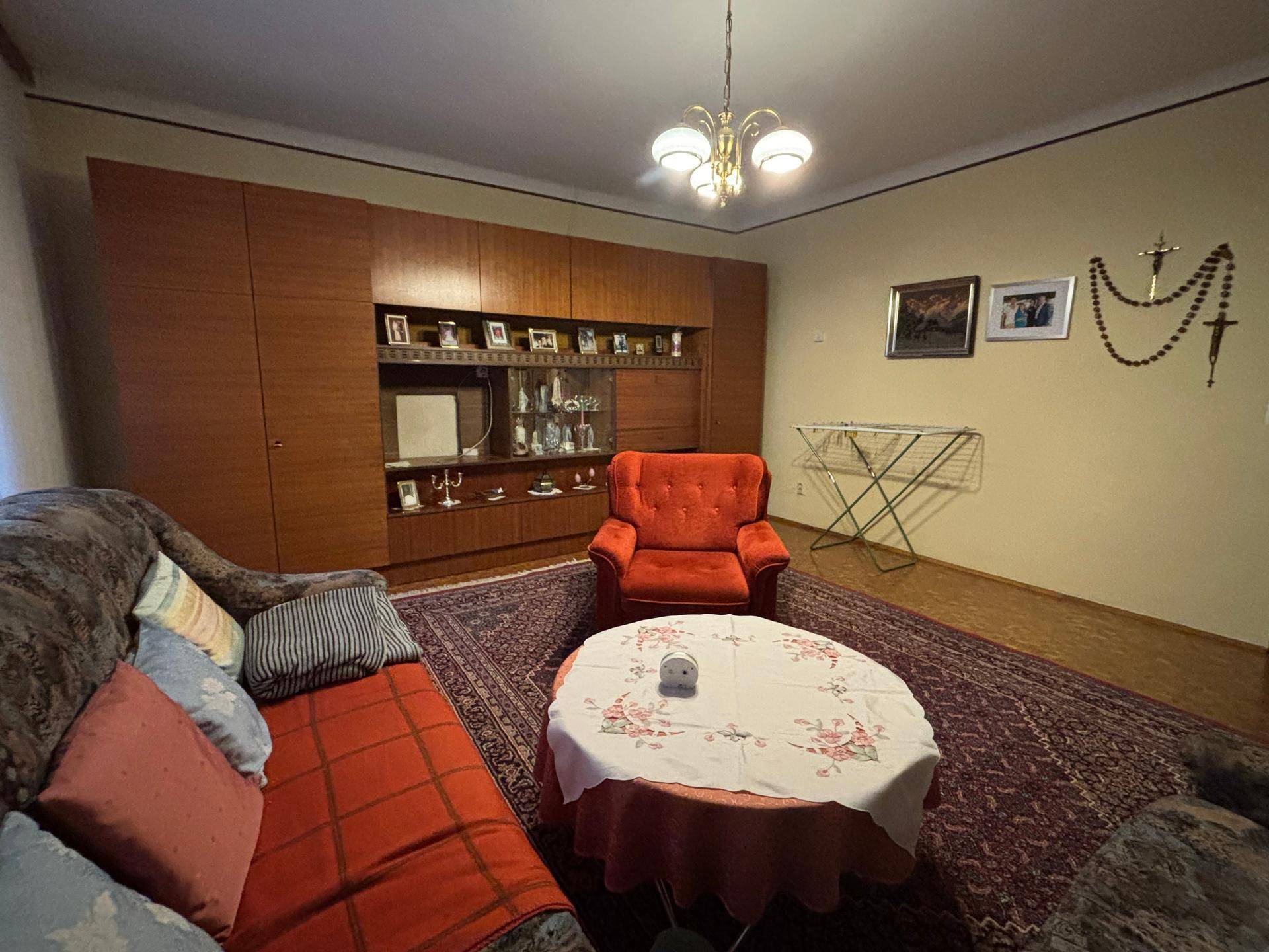 Wohnzimmer mit traditioneller Einrichtung, großem Teppich und einer Holzschrankwand mit Dekorationen.