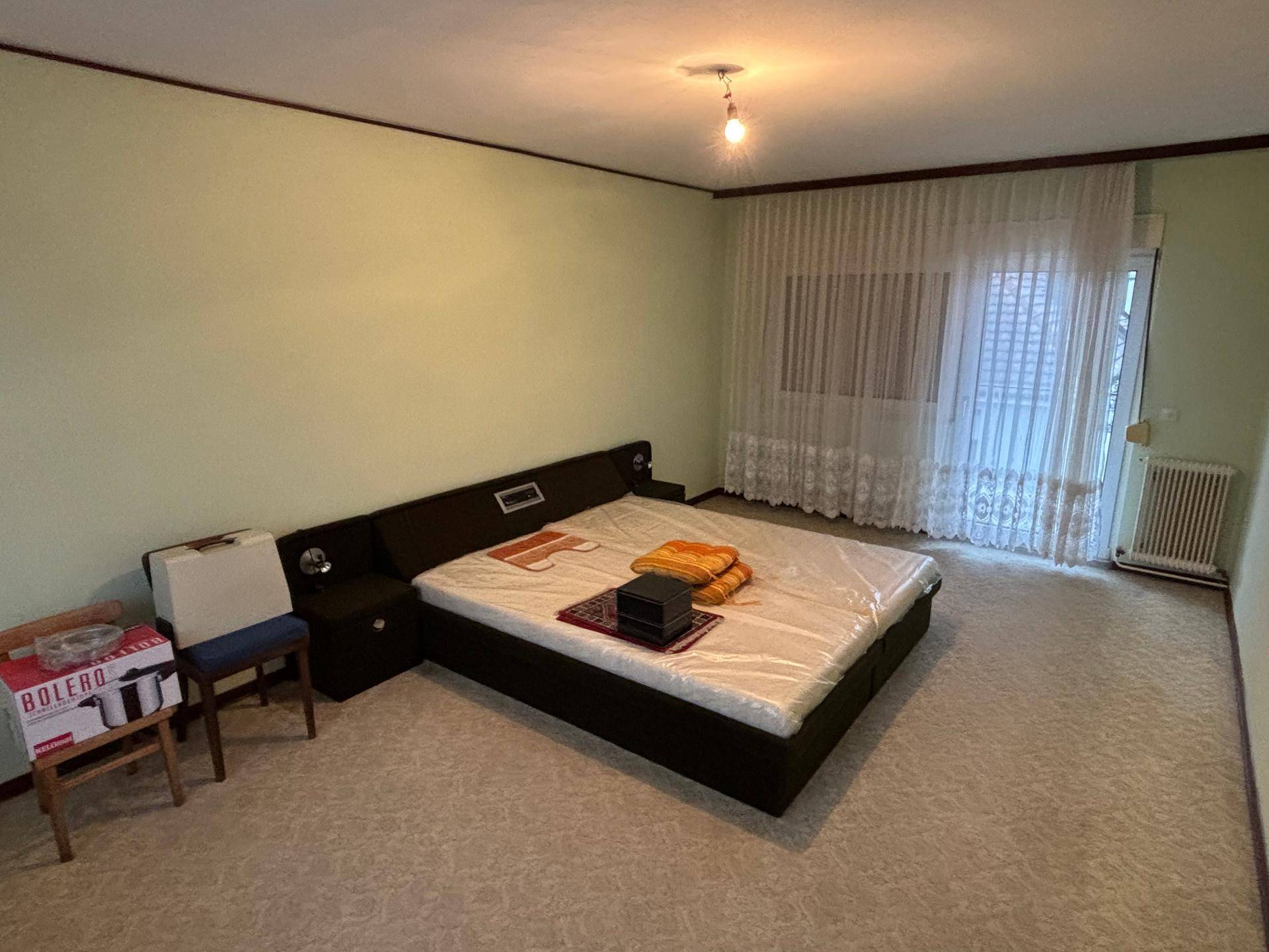 Schlafzimmer mit Doppelbett, Teppichboden und hellgrünen Wänden, bereit zur individuellen Gestaltung.