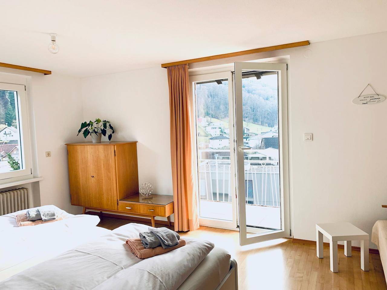 Helles Schlafzimmer mit Balkonzugang und Blick auf die umliegende Hügellandschaft.