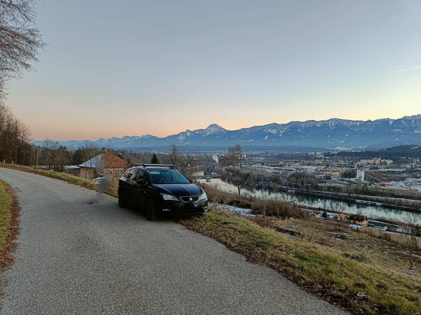Weitläufige Aussicht über das Tal mit einem Fluss, einer Stadt und einer beeindruckenden Bergkette am Horizont.