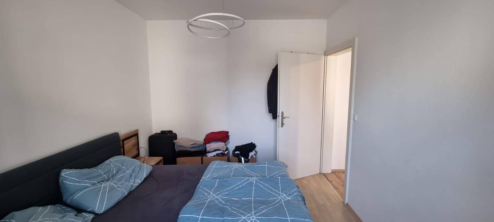 Schlichtes Schlafzimmer mit Holzboden und viel Tageslicht.