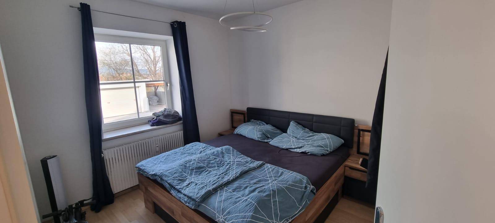 Schlafzimmer mit Doppelbett, Holzboden und Fenster mit Blick ins Grüne.