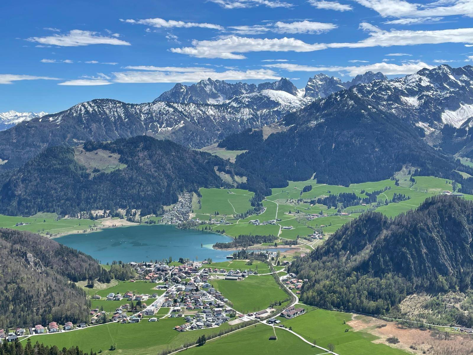 Atemberaubender Panoramablick auf ein Tal mit See, Dörfern und schneebedeckten Bergen.