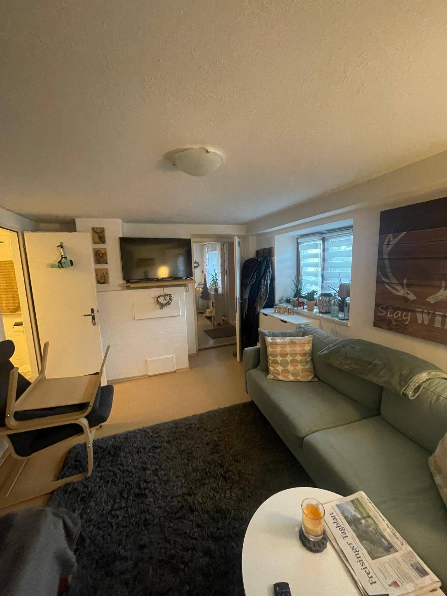 Wohnbereich mit bequemer Couch, Fernseher und Blick auf den Eingangsbereich.