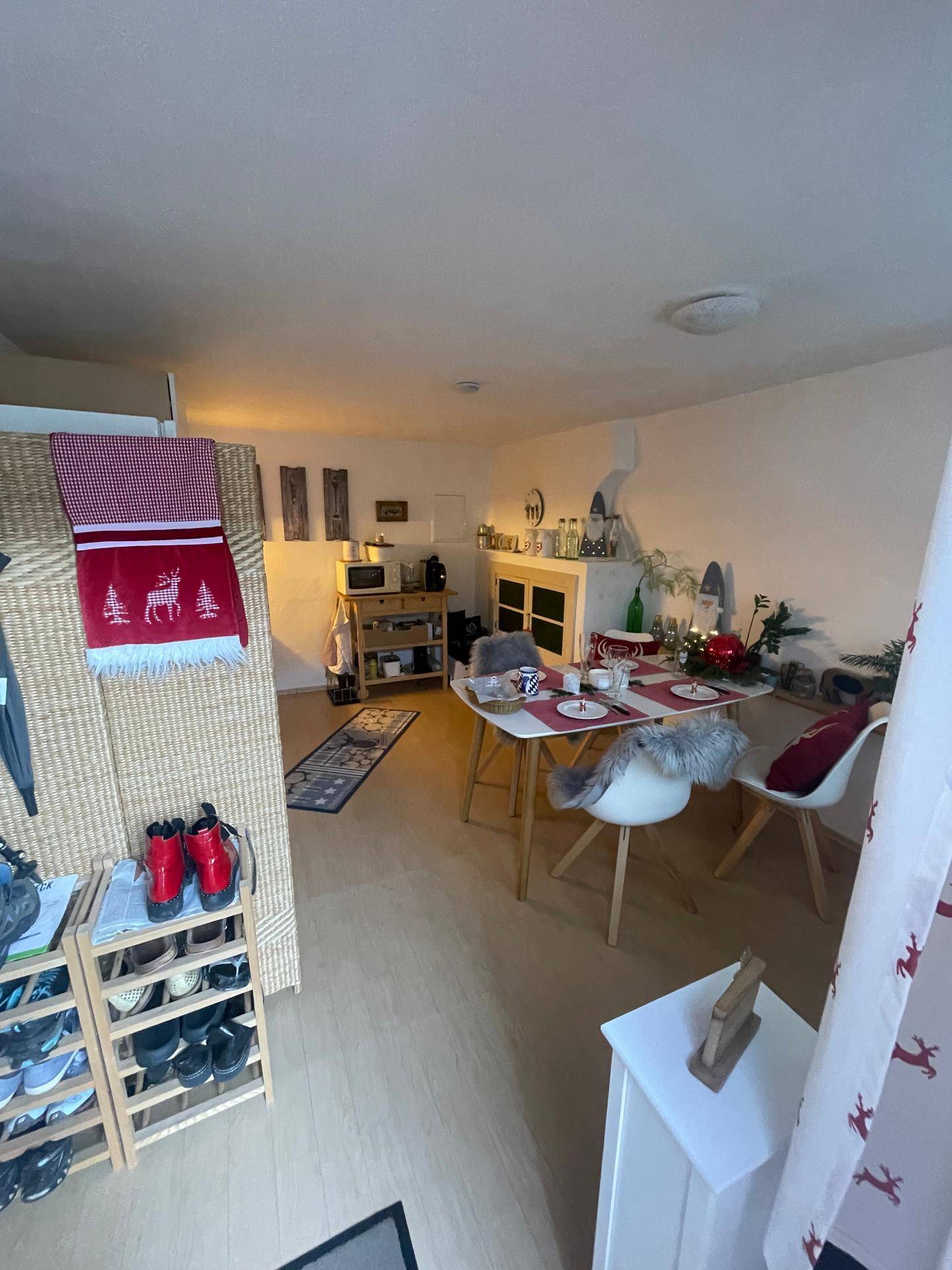 Blick auf den Essbereich und die Küchenzeile, mit einem Schuhregal im Vordergrund.