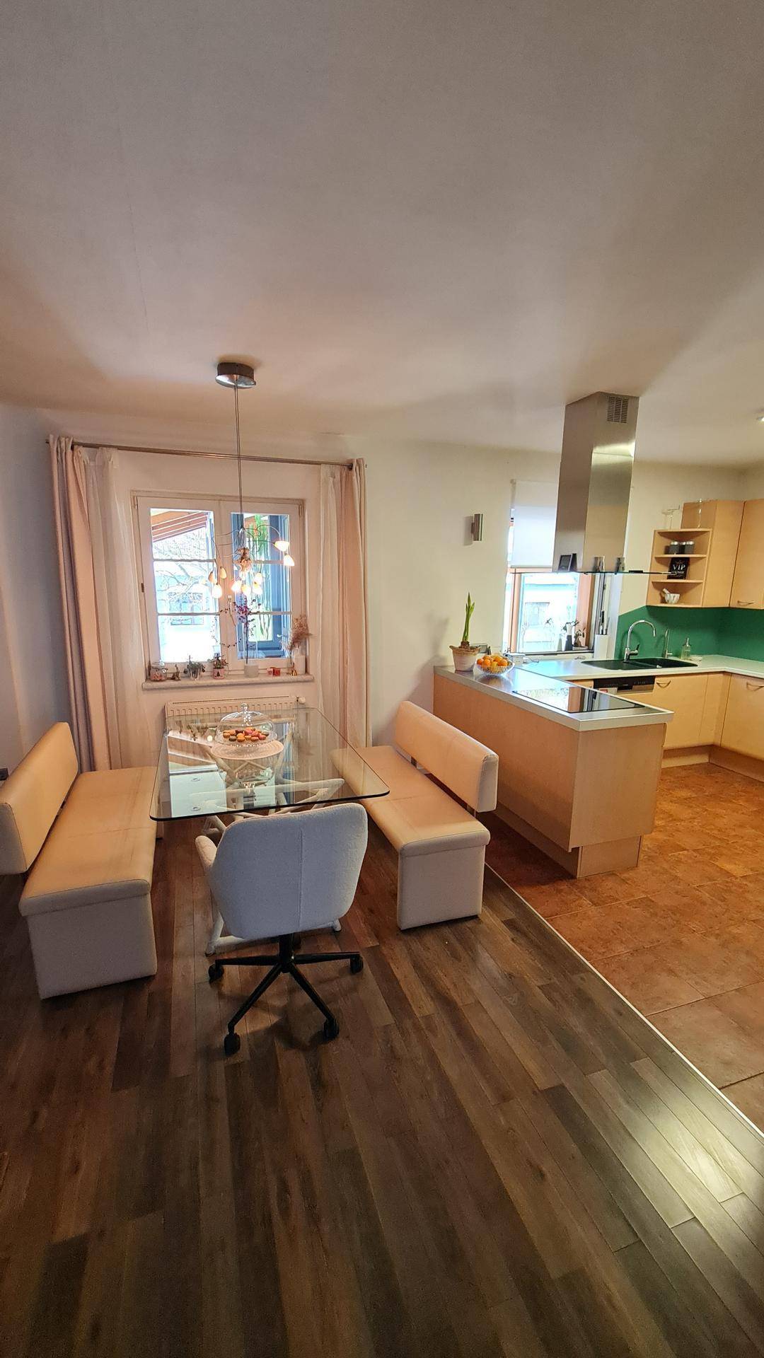 Essbereich mit Glas-Esstisch und Blick auf die moderne offene Küche.