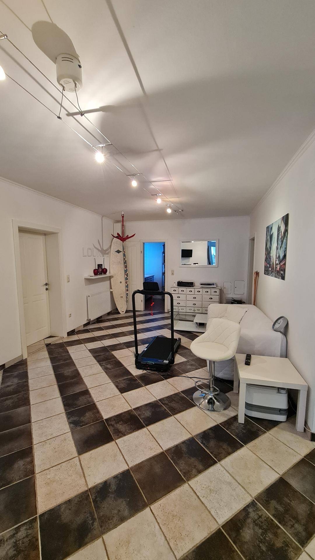 Mehrzweckraum mit gemustertem Fliesenboden und Fitnessgerät.