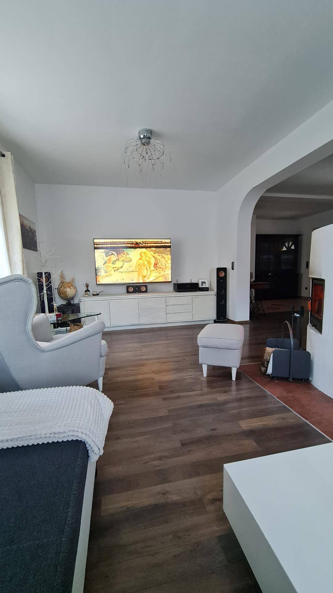 Geräumiges Wohnzimmer mit Fernseher, Sofa und Holzboden.
