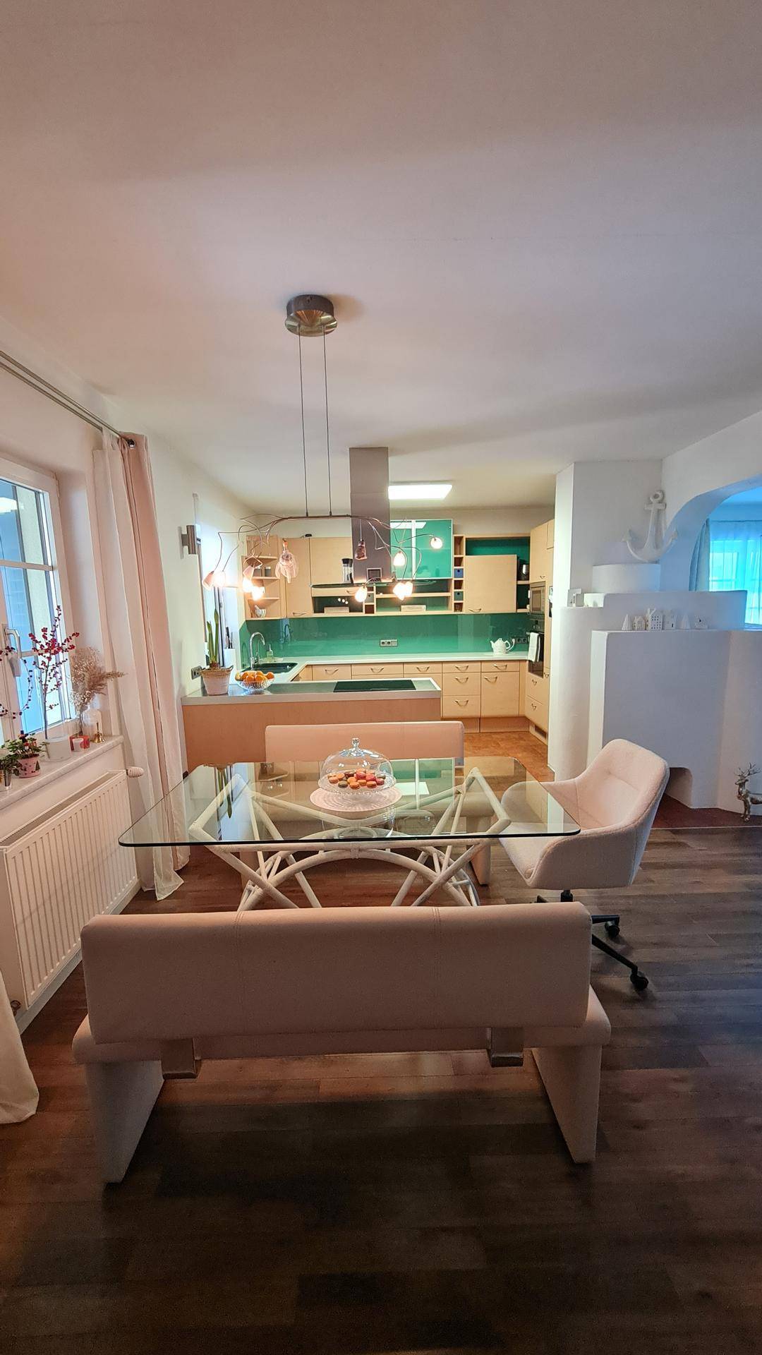 Offener Wohn-Essbereich mit moderner Küche, Glas-Esstisch und Holzboden.