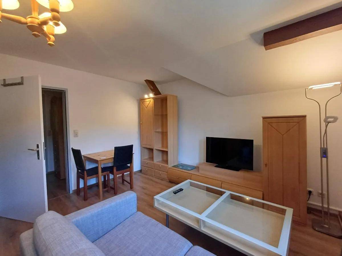 Heller Wohn-Essbereich mit Holzboden, Sofa und Esstisch, der Zugang zu einem weiteren Raum bietet.