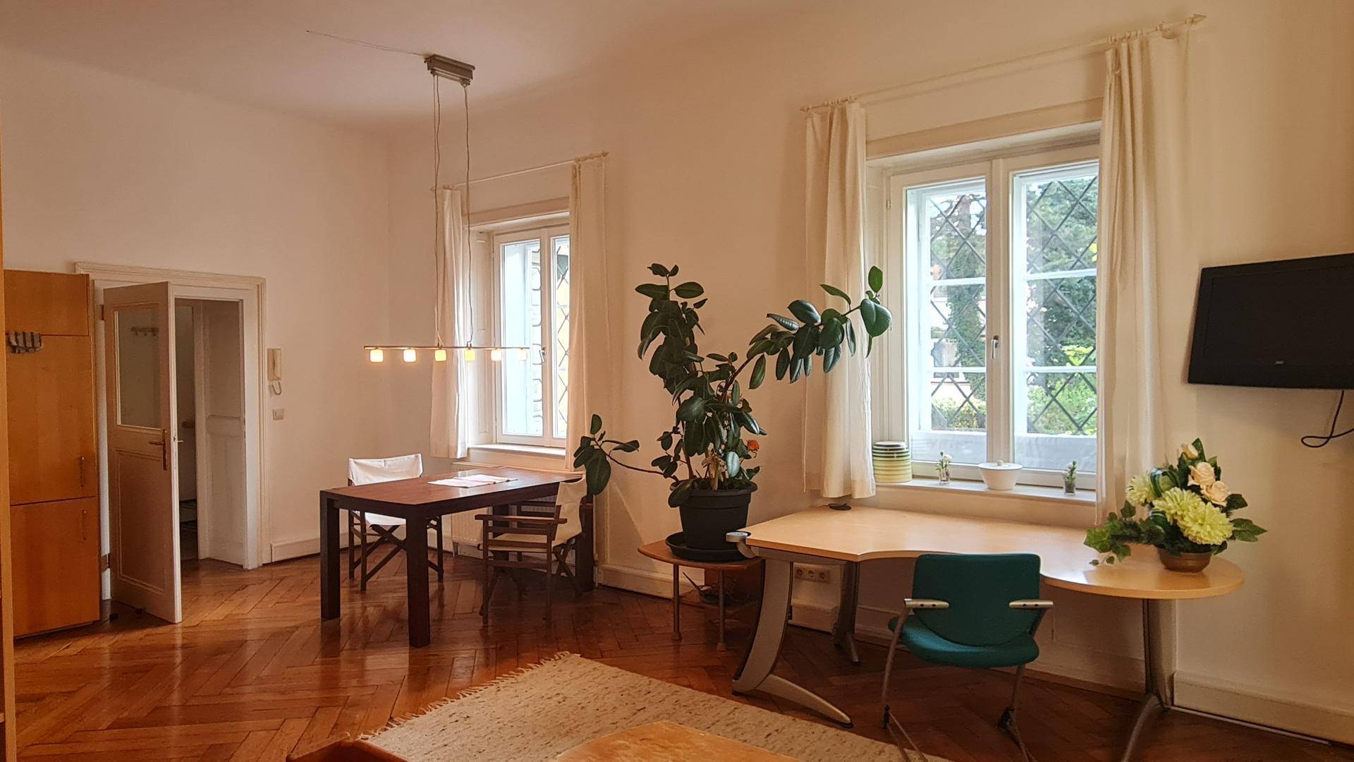 Geräumiger Wohn- und Essbereich mit Parkettboden, Esstisch und hellem Arbeitsplatz.