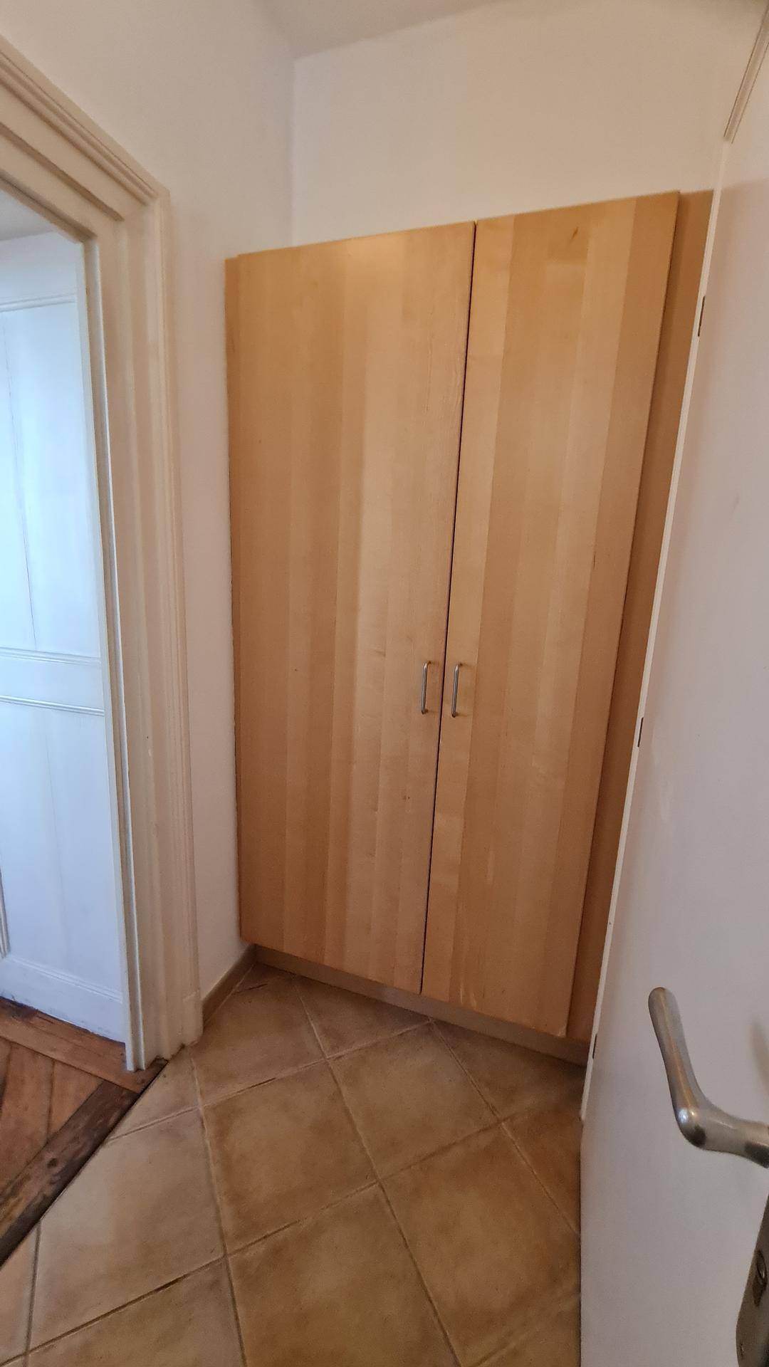 Heller Flur mit Holzschrank und Fliesenboden im Eingangsbereich.