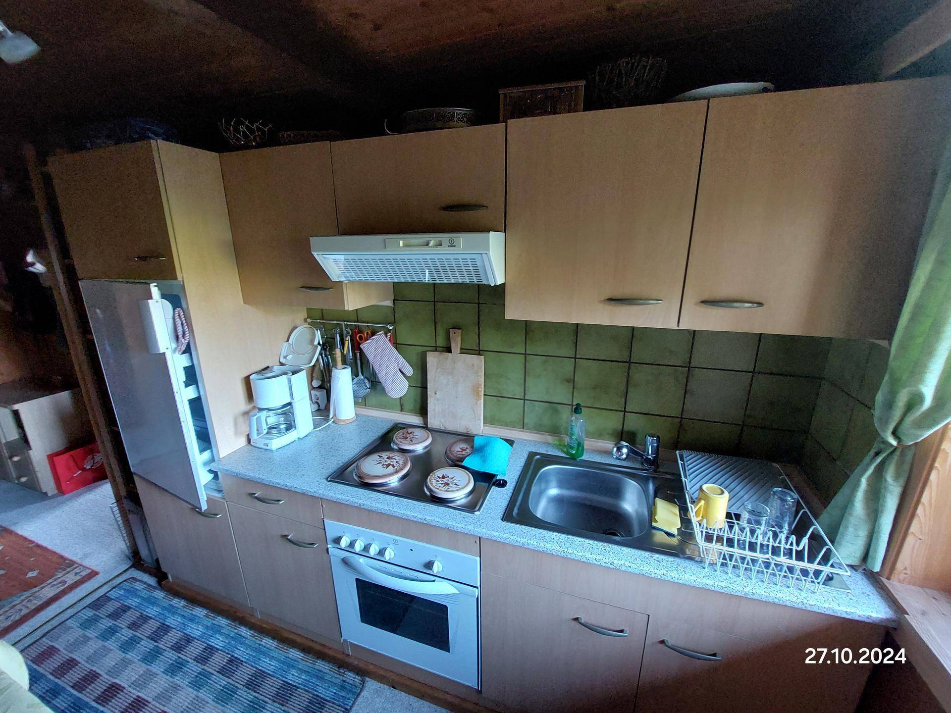 Detailansicht der Küche mit Spüle, Herd, Backofen und Kühlschrank.