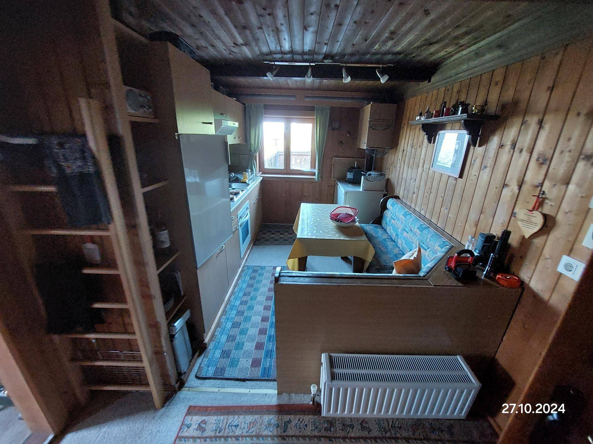 Kleine Küche mit Holzvertäfelung, Essbereich und einfachen Küchengeräten.