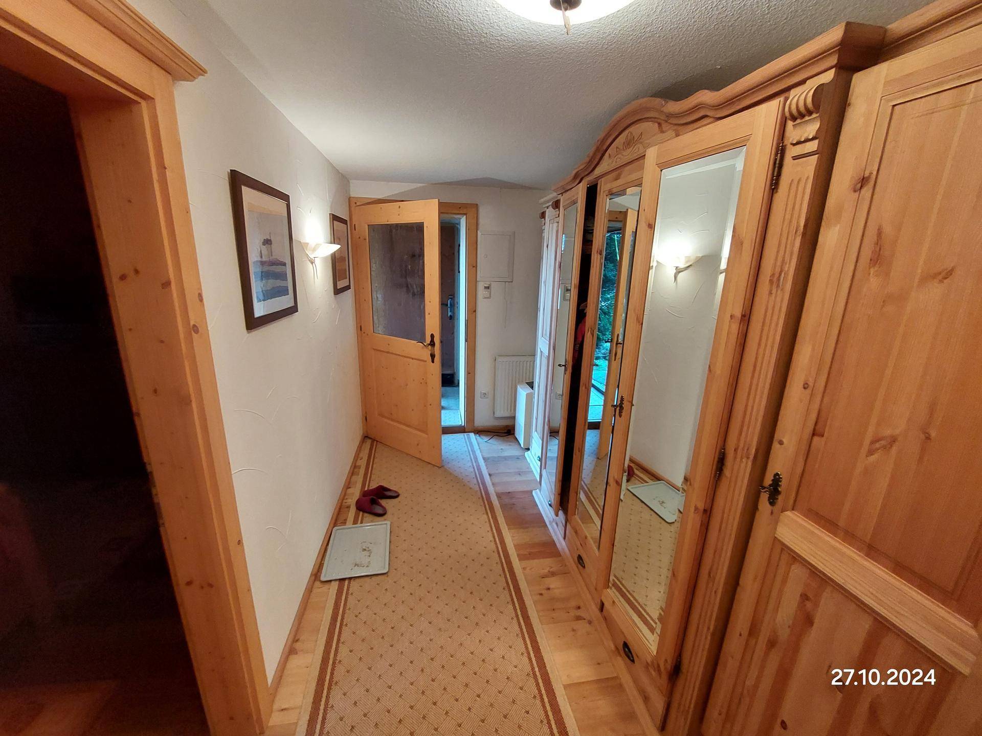 Heller Flur mit Holzvertäfelung, einem großen Spiegelschrank und Holztüren.