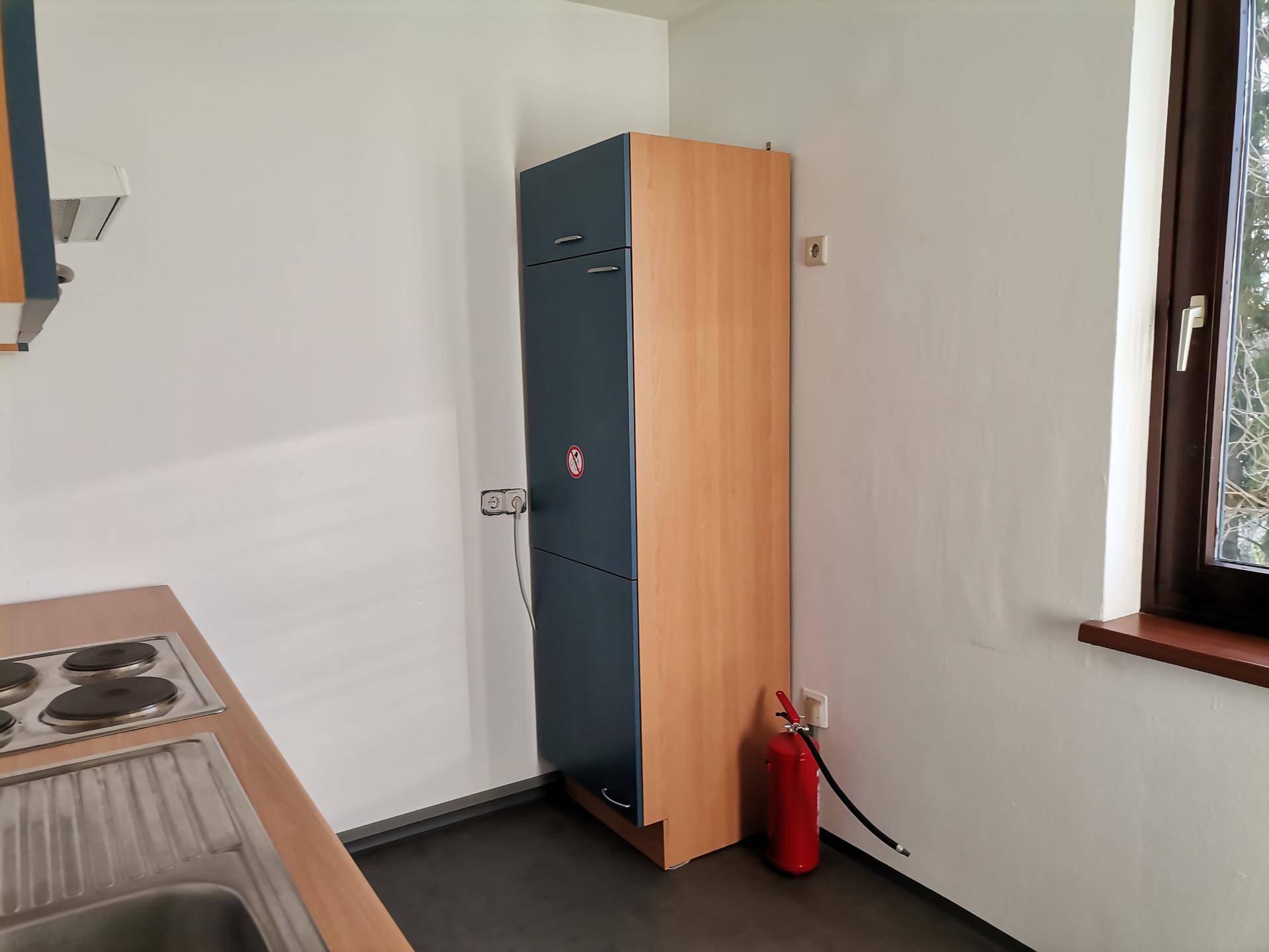 Detailansicht der Küchenzeile mit Fenster und einem hohen Schrank.