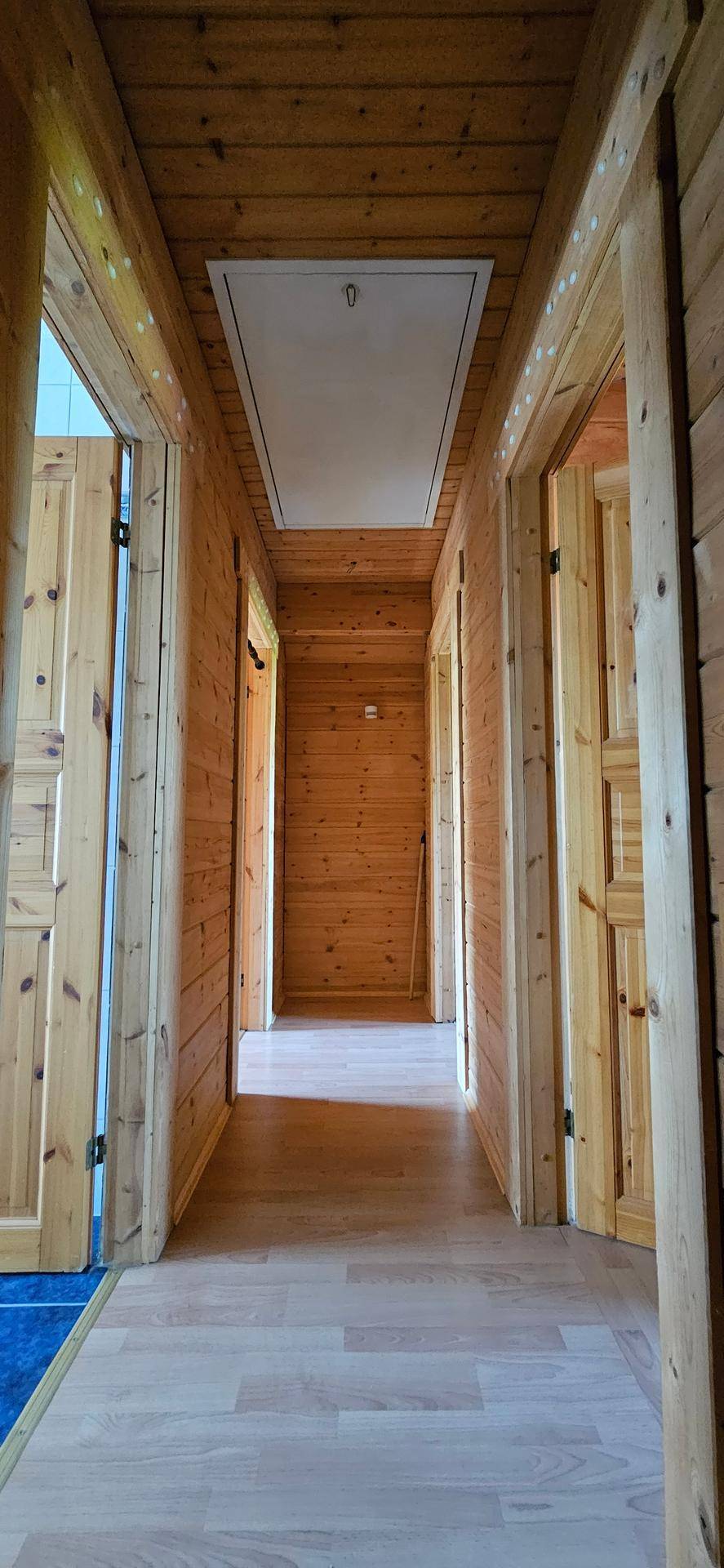 Langer Flur mit Holzvertäfelung an Wänden und Decke sowie hellem Holzboden.