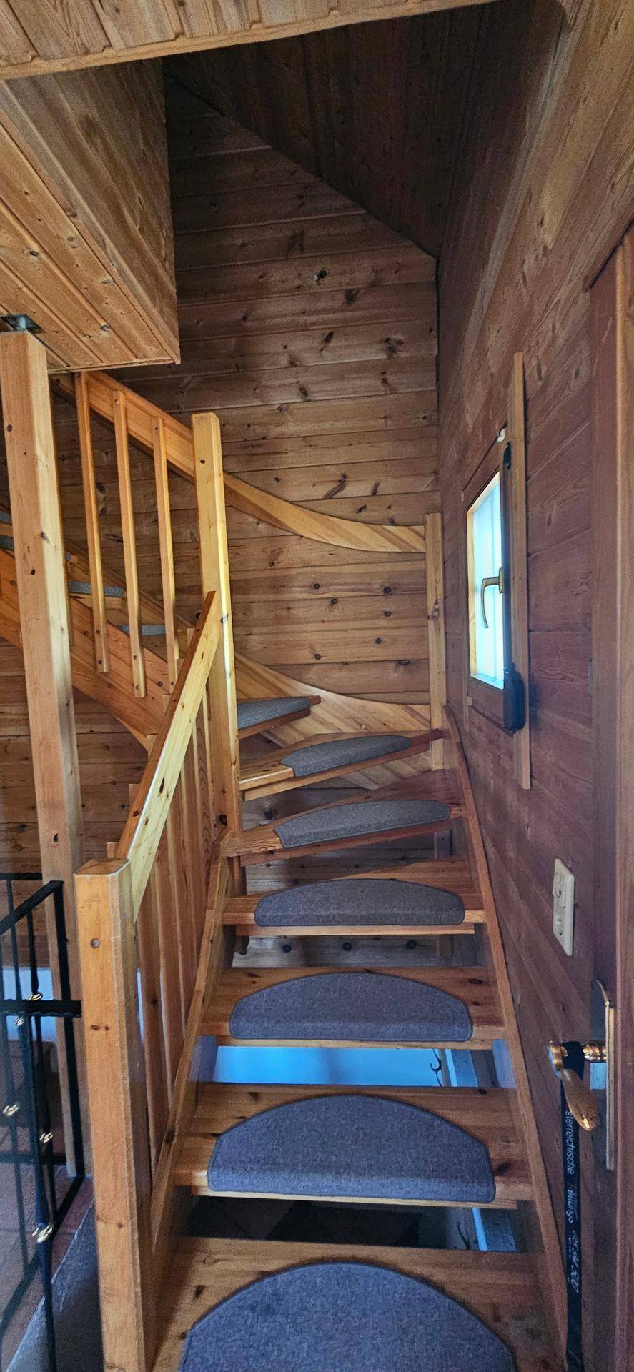 Holztreppe mit Teppichstufen führt in die oberen Etagen des Hauses.