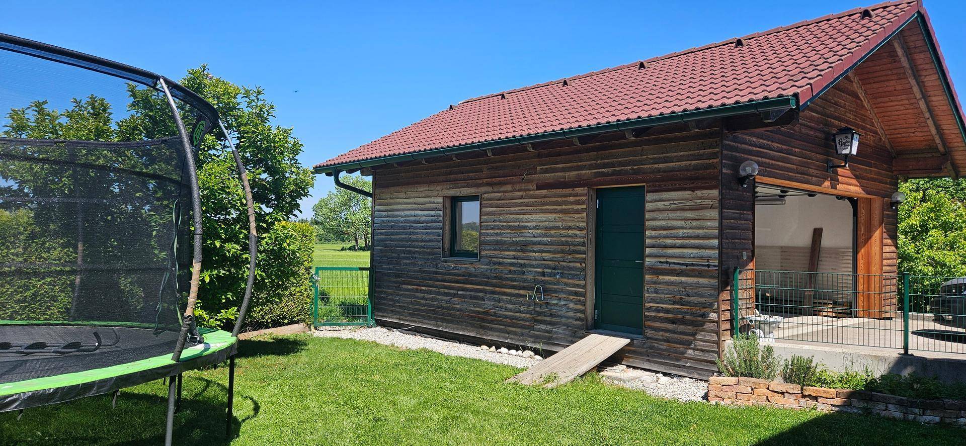 Hinterer Gartenbereich mit Trampolin und angrenzender Garage des Holzhauses.