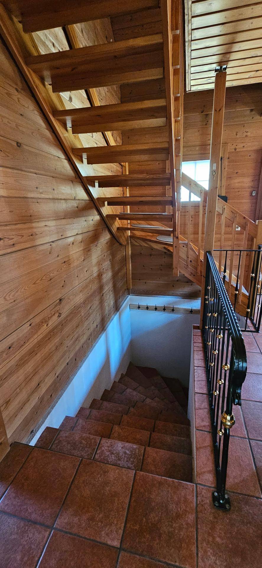 Holztreppe führt hinunter in den Kellerbereich, umgeben von Holzvertäfelung.