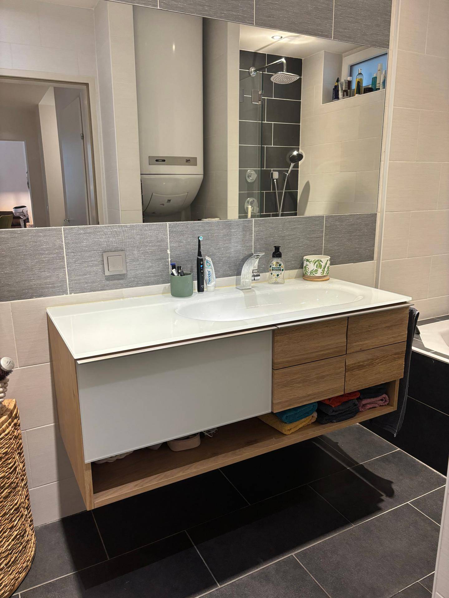 Modernes Badezimmer mit schwebendem Waschtisch, großem Spiegel und begehbarer Dusche.