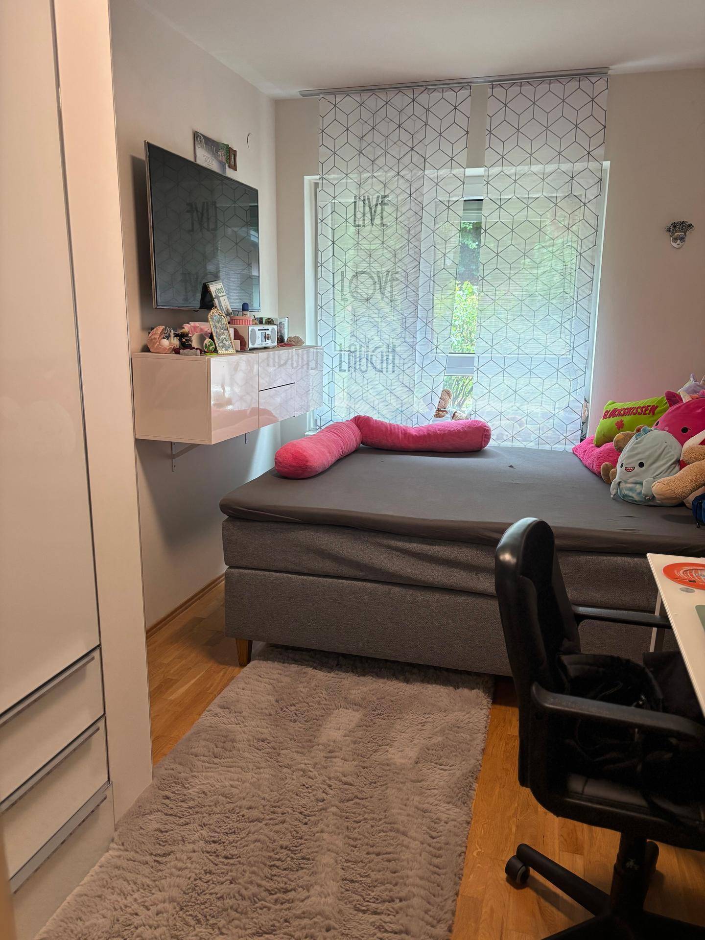 Kinderzimmer mit Einzelbett, Fernseher und Fenster mit Blick nach draußen.