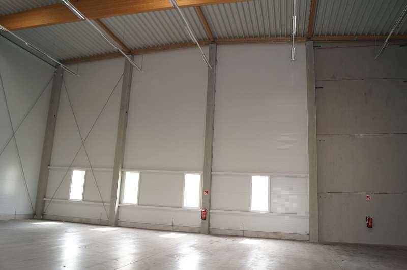 Leere Lagerhalle mit hohen Wänden, kleinen Fenstern und Betonboden, bereit zur Nutzung.