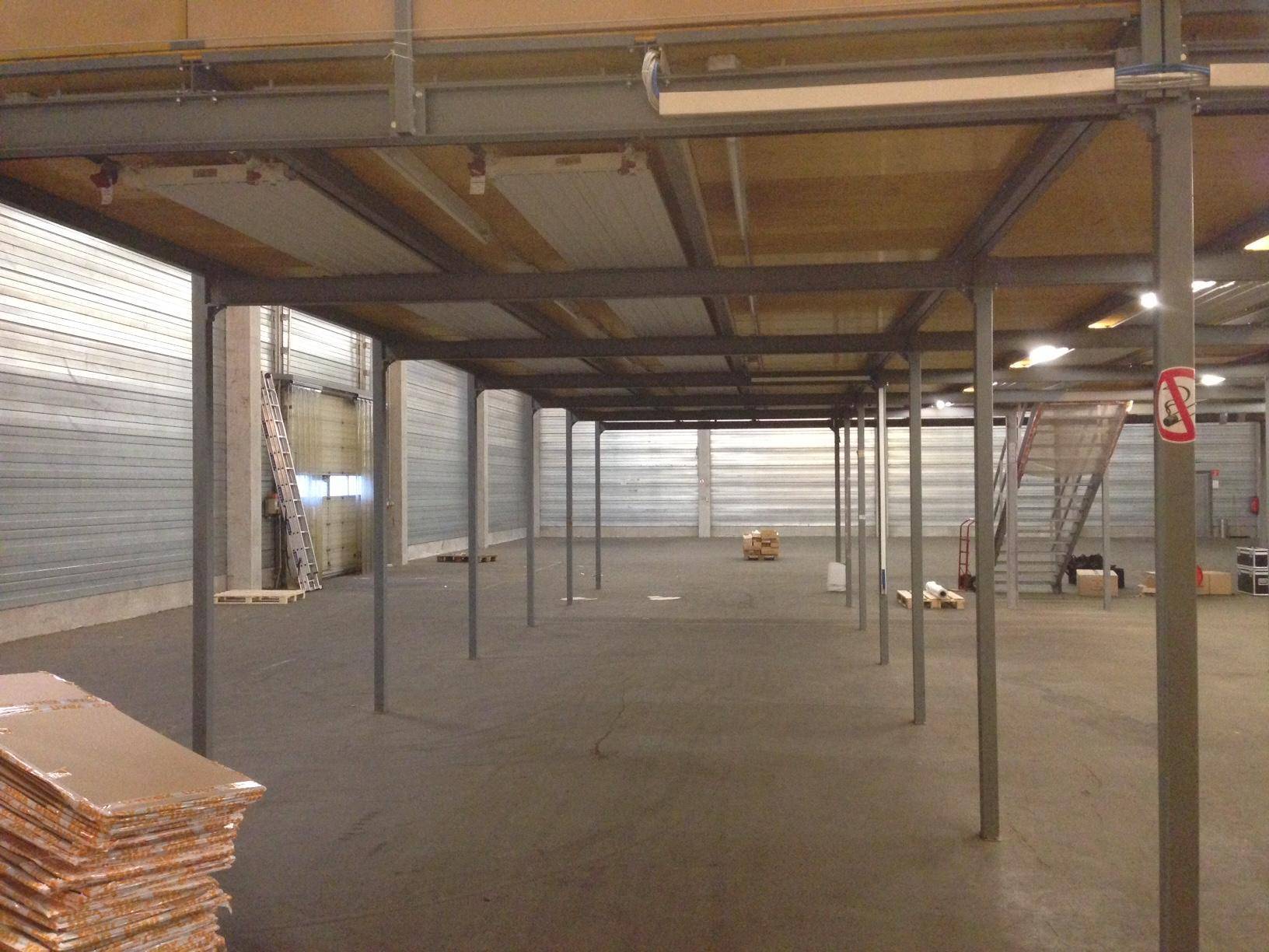 Weitläufige Lagerhalle mit Zwischengeschoss-Konstruktion aus Metall und Holz, viel Platz.