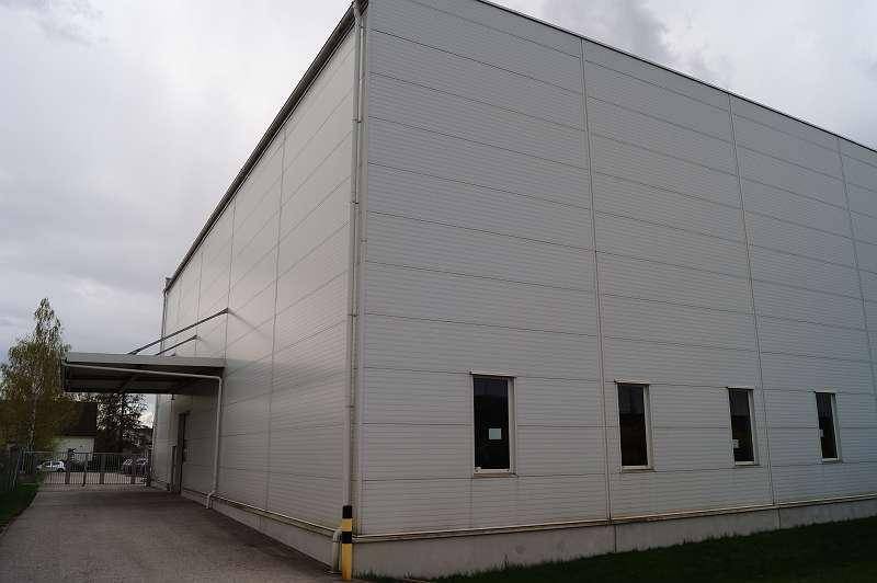 Große Lagerhalle mit Metallfassade und Überdachung über einem Eingangsbereich.