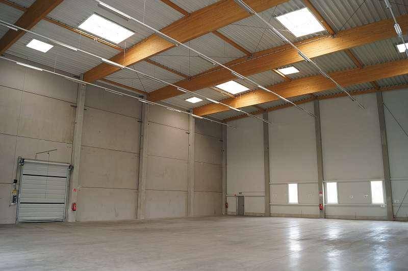 Geräumige Lagerhalle mit hoher Decke, Holzbalken und Oberlichtern, bereit zur Nutzung.