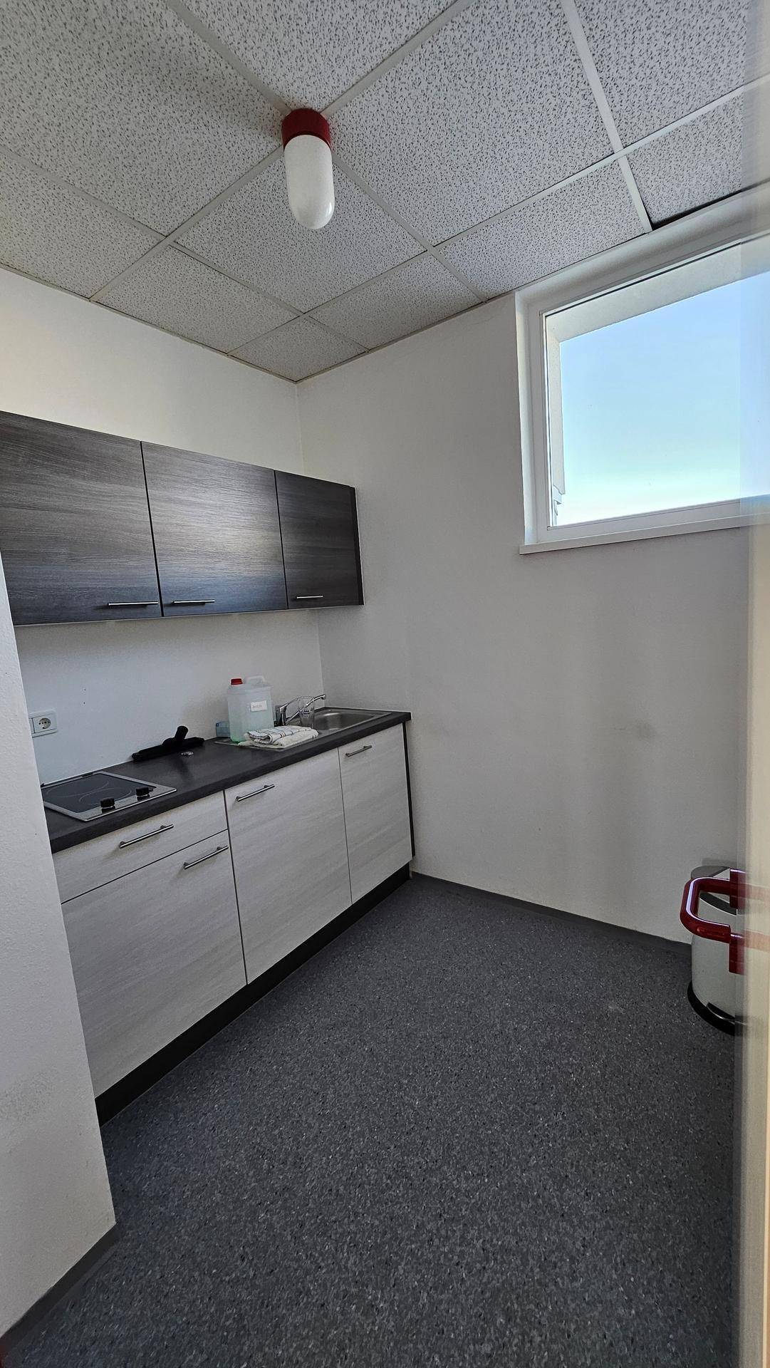 Kleine Küchenzeile mit Spüle, Kochfeld und Hängeschränken, ideal für Pausen.