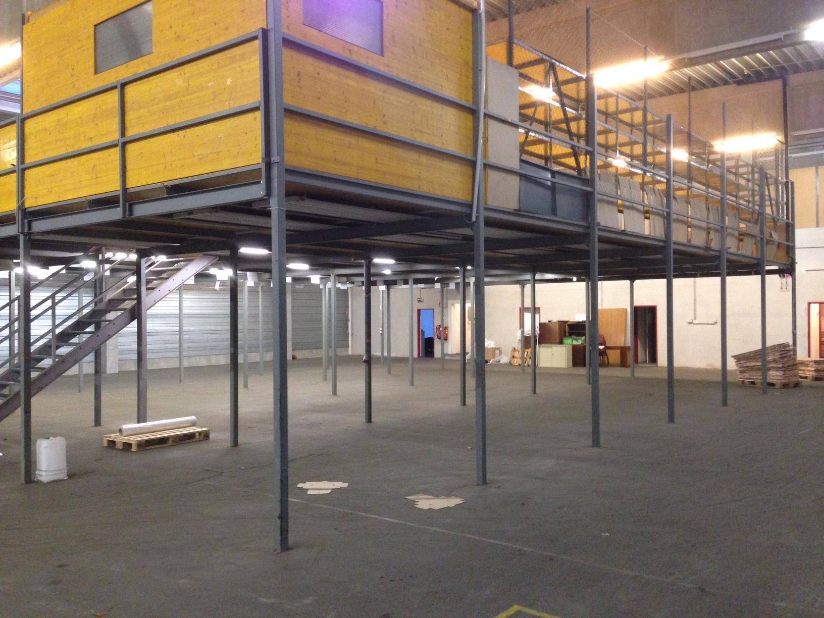 Lagerhalle mit großer Zwischengeschoss-Konstruktion aus Metall und Holz, mit Treppe und Bürobereich.
